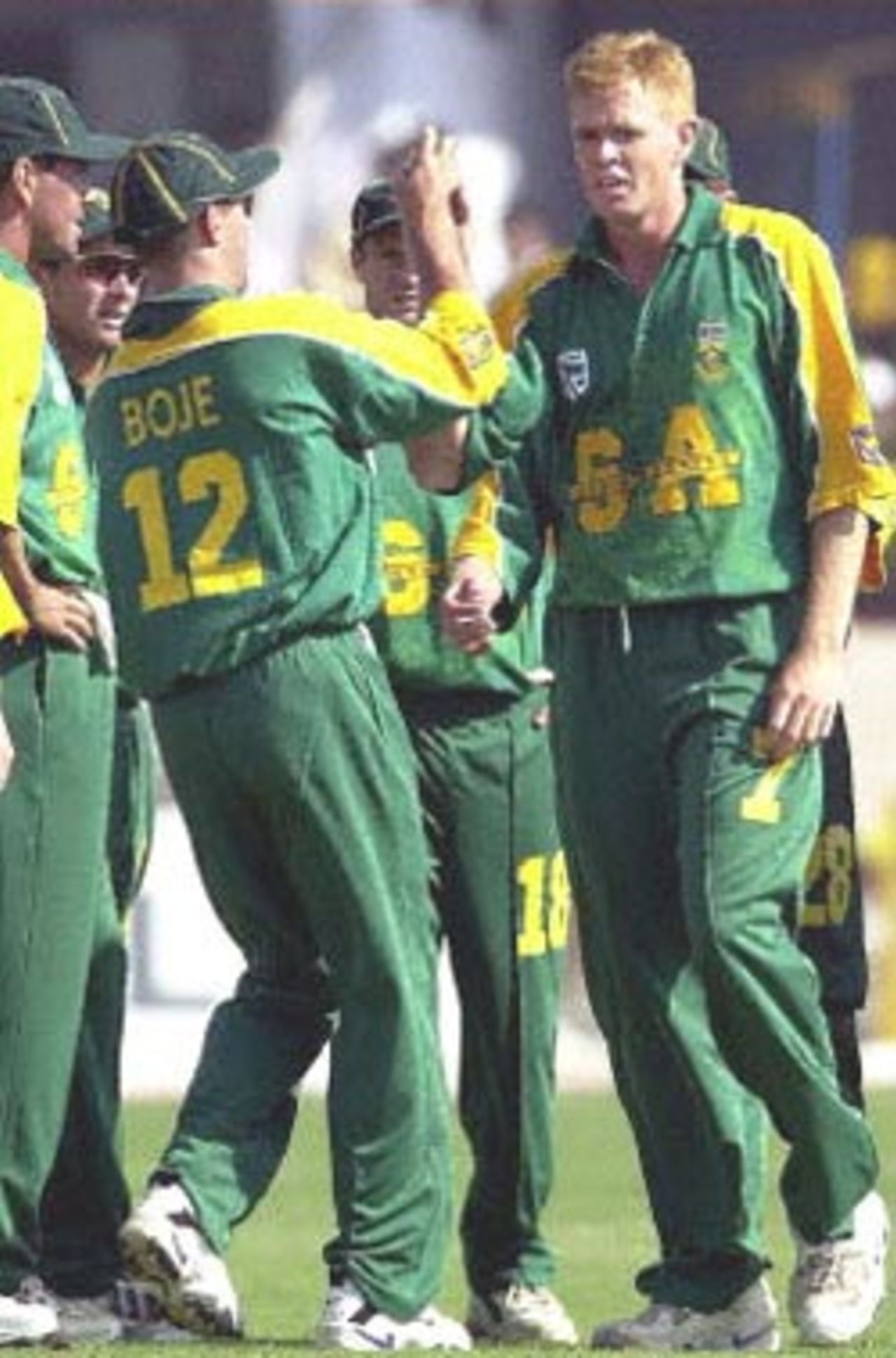 South African cricketer Nicky Boje (No.12) congratulates team-mate Shuan Pollock (R) for claiming Indian batsman Sachin Tendulkar's wicket as the rest of the team join in to celebrate during the third one-day cricket international between India and South Africa played at Faridabad, 15 March 2000. South Africa went on to beat India by two wickets in a close finish.