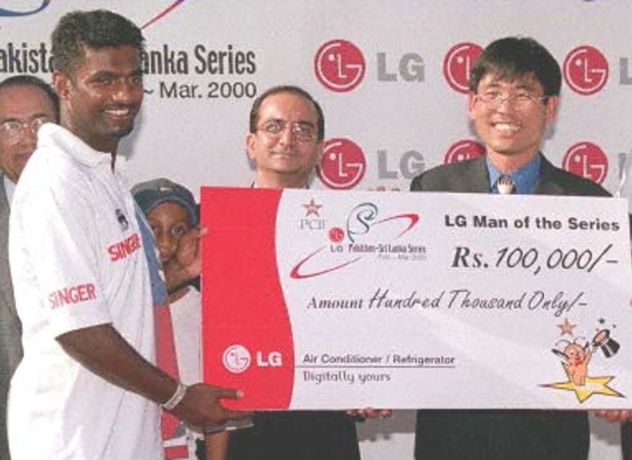 Sri Lankan off-spin-bowler Muttiah Muralitharan (L) receives man- of-the-series award from J.Y Chan (R), marketing manager of South Korean electronic company, LG electronic at the end of the third and final cricket Test in Karachi, 15 March 2000. Muralitharan took a record of 26 wickets in a three-match series against Pakistan. Others in the picture are unidentified.