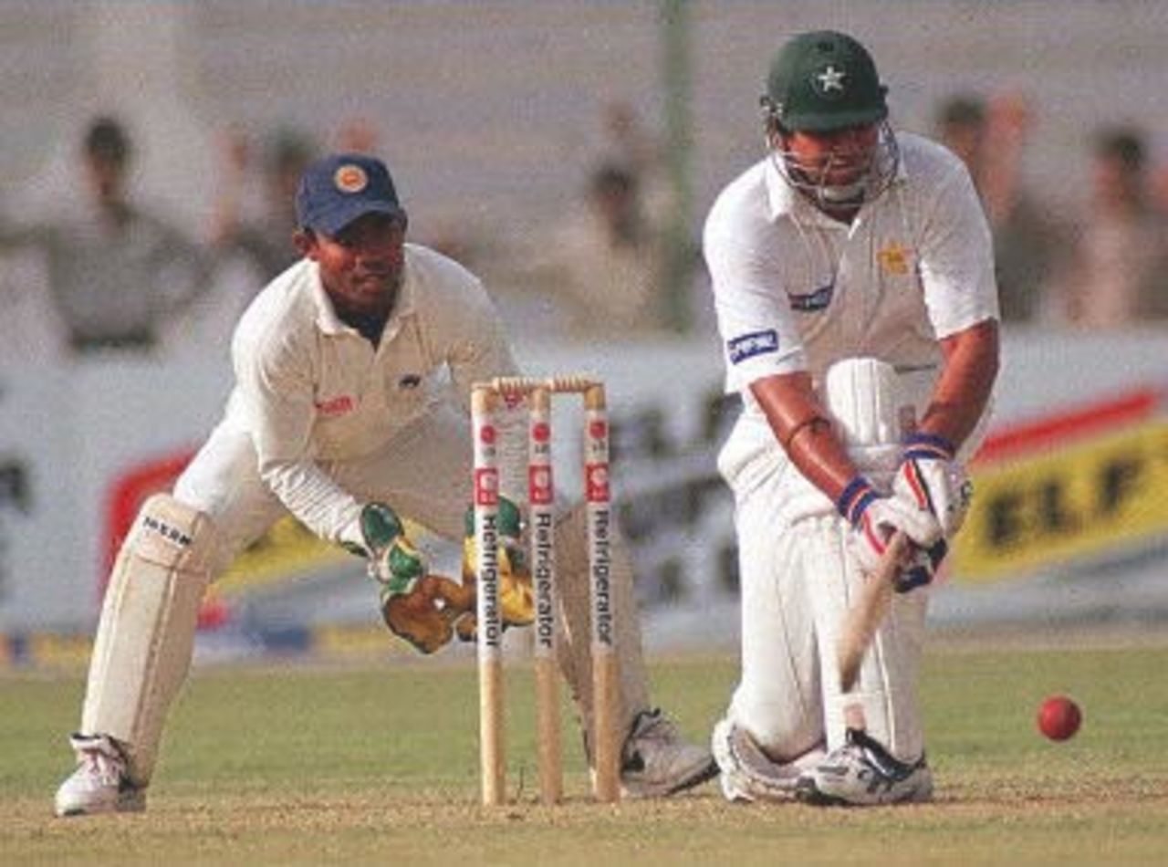 Pakistani batsman Inzamam-ul-Haq (R) sweeps for a boundary as Sri Lankan wicketkeeper Romesh Kaluwitharana looks on during the first day of the third cricket Test against Sri Lanka in Karachi 12 March 2000. Haq's polished knock of 86 helped Pakistan score 256 in their first innings.
