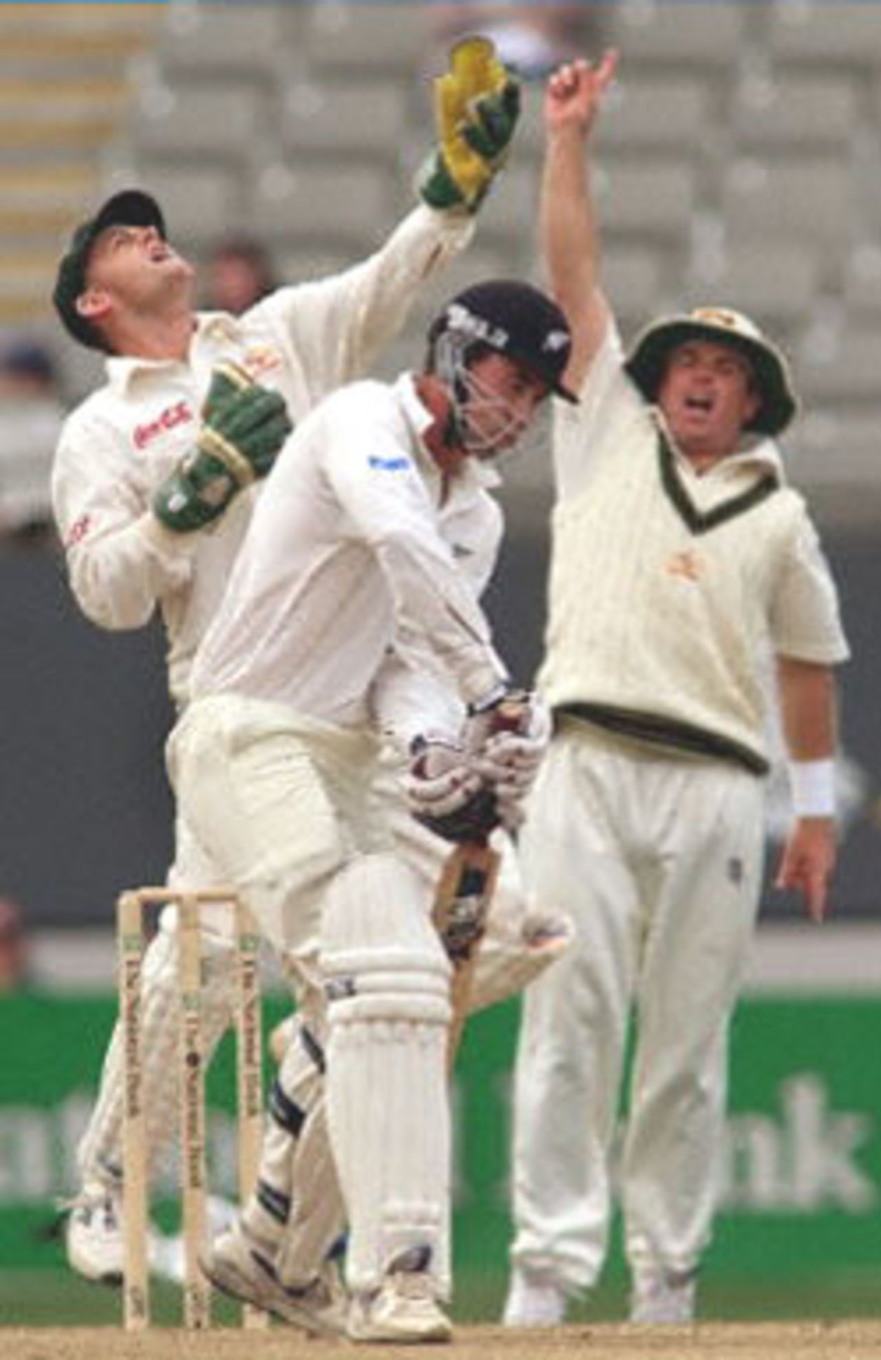 Australian wicketkeeper Adam Gilchrist (L) celebrates catching and dismissing New Zealand batsman Stephen Fleming (C) with Shane Warne (R) on the third day of the first Test Match being played at Eden Park in Auckland, 13 March 2000. New Zealand, who is chasing 281 runs for victory, are 151-5 at stumps.