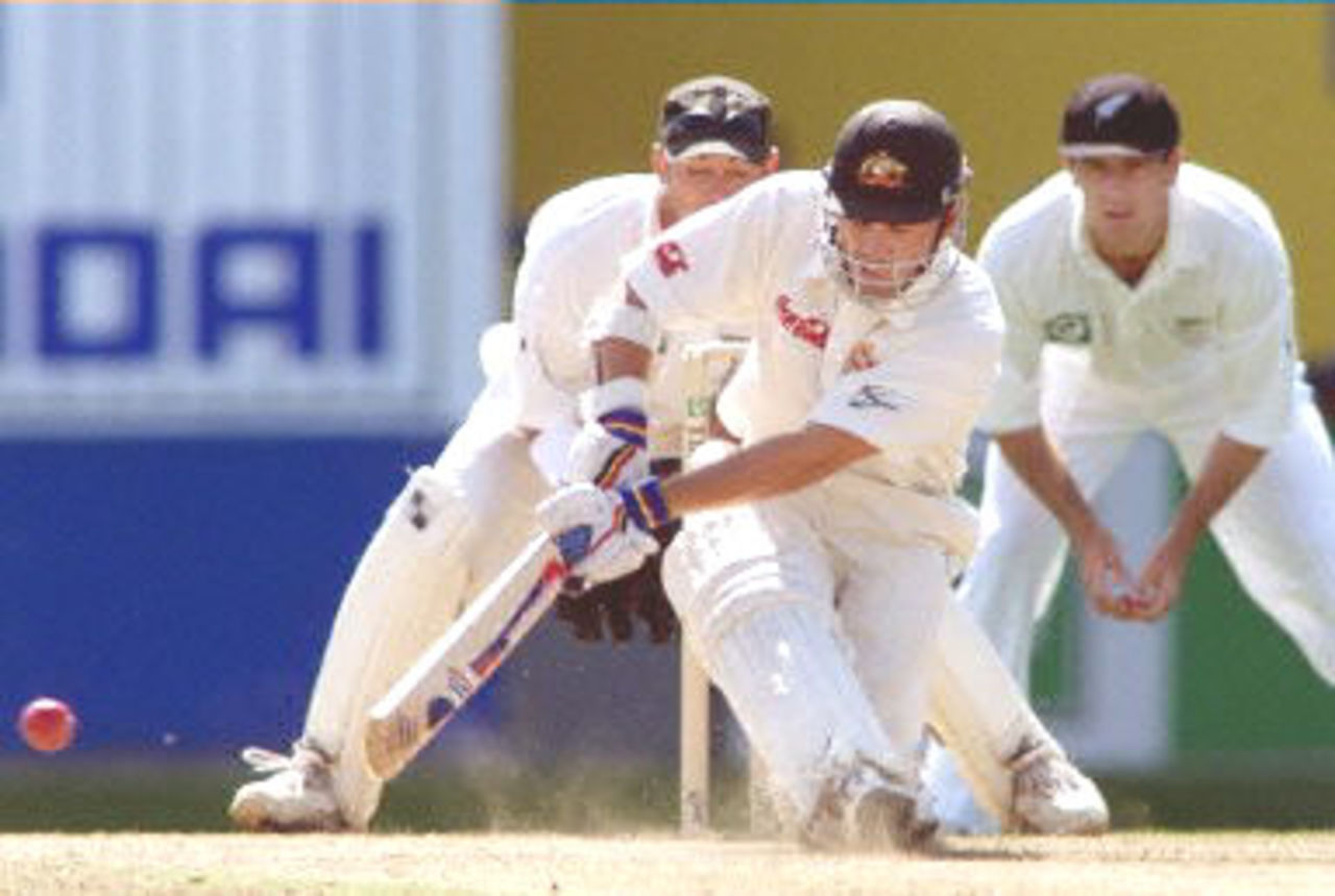 Australian batsman Justin Langer (C) sweeps to the outfield as New Zealand wicketkeeper Adam Parore (L) and Craig Spearman (R) look on during the second day of the first Test match played at Eden Park in Auckland 12 March 2000. Australia dismissed New Zealand for 163 in their first innings and Australia in their second innings is 114-5 for a lead of 165 runs at stumps.