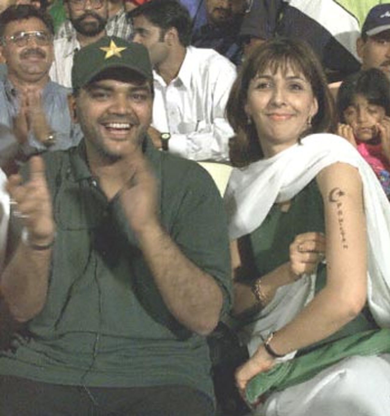 Pakistan cricket team supporter Kishver Niazi (R) shows a temporary tattoo of the Pakistani flag emblem during the final between Pakistan and South Africa in Sharjah.