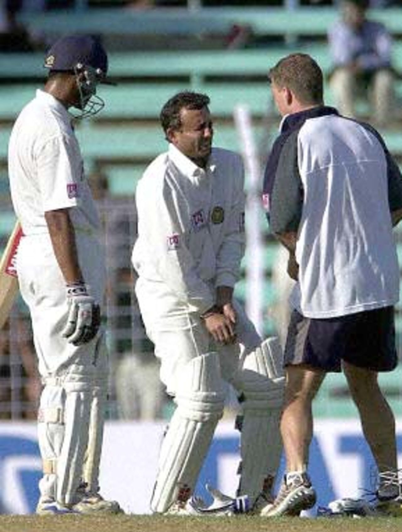Indian batsman Nayan Mongia (C),tended by the team's physio Andrew Leipus (R), grimaces in pain after being hit by a delivery from Australian speedster Jason Gillespie, while team-mate Rahul Dravid looks on during India's second innings on the second day of the first test match between India and Australia at the Wankhade stadium in Mumbai 28 February 2001. India were 58 for 2 at close of play in their second innings after conceding a 173 runs lead to Australia in the first innings.