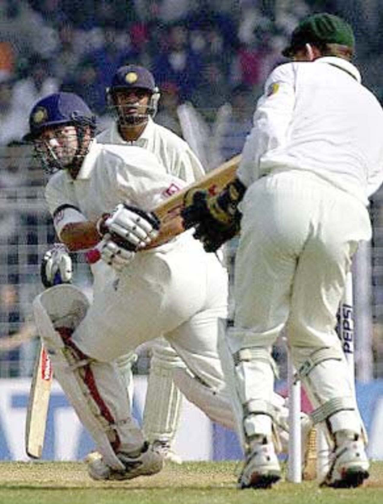Indian batsman Sachin Tendulkar (L) sweeps a delivery from Australian spinner Shane Warne (not in the picture) as team-mate Rahul Dravid (C) and Australian wicketkeeper Adam Gilchrist look on during third day's play of the first test match between India and Australia at the Wankhade stadium in Mumbai 01 March 2001. Tendulkar was playing at 29 to steady India's second innings at 103 for 2 after conceding a 173 runs lead to Australia in the first innings.