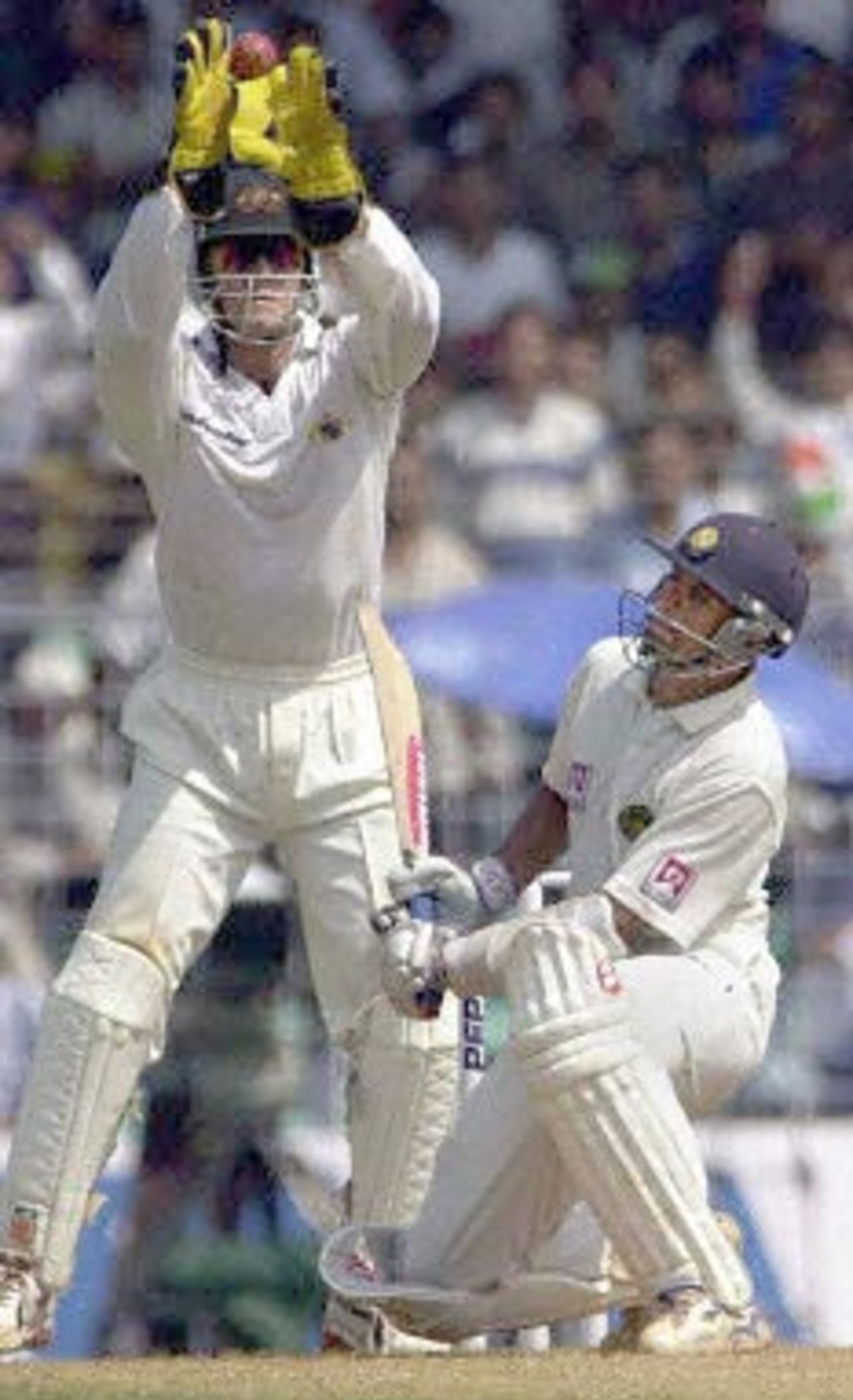 Indian batsman Rahul Dravid ducks as Australian wicketkeeper Adam Gilchrist jumps to catch a bouncer from Australian paceman Damien Fleming during the third day's play of the first test match between India and Australia at the Wankhade stadium in Mumbai 01 March 2001. Dravid was unbeaten at 26 as India went to lunch without losing a wicket in the first two hours of play, after conceding a 173 runs lead to Australia in the first innings.