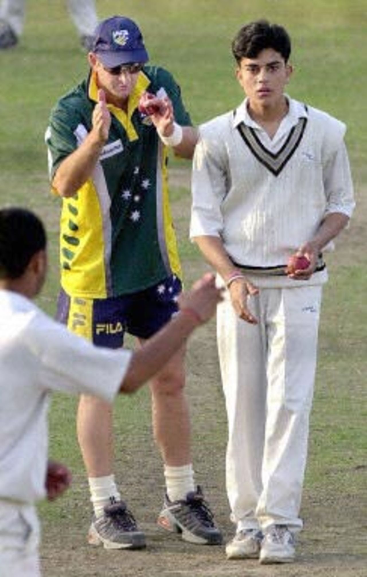 Australian star batsman Mark Waugh (C-green top) gives finer tips to a young Indian junior cricketer as he runs in to bowl during a net practice session by the Australian team at Ferozshah Kotla ground in New Delhi, 04 March 2001. Australia will be playing India's Board President's XI team from 06 March 2001 after having already taken a 1-0 lead in the three Test match series against India.