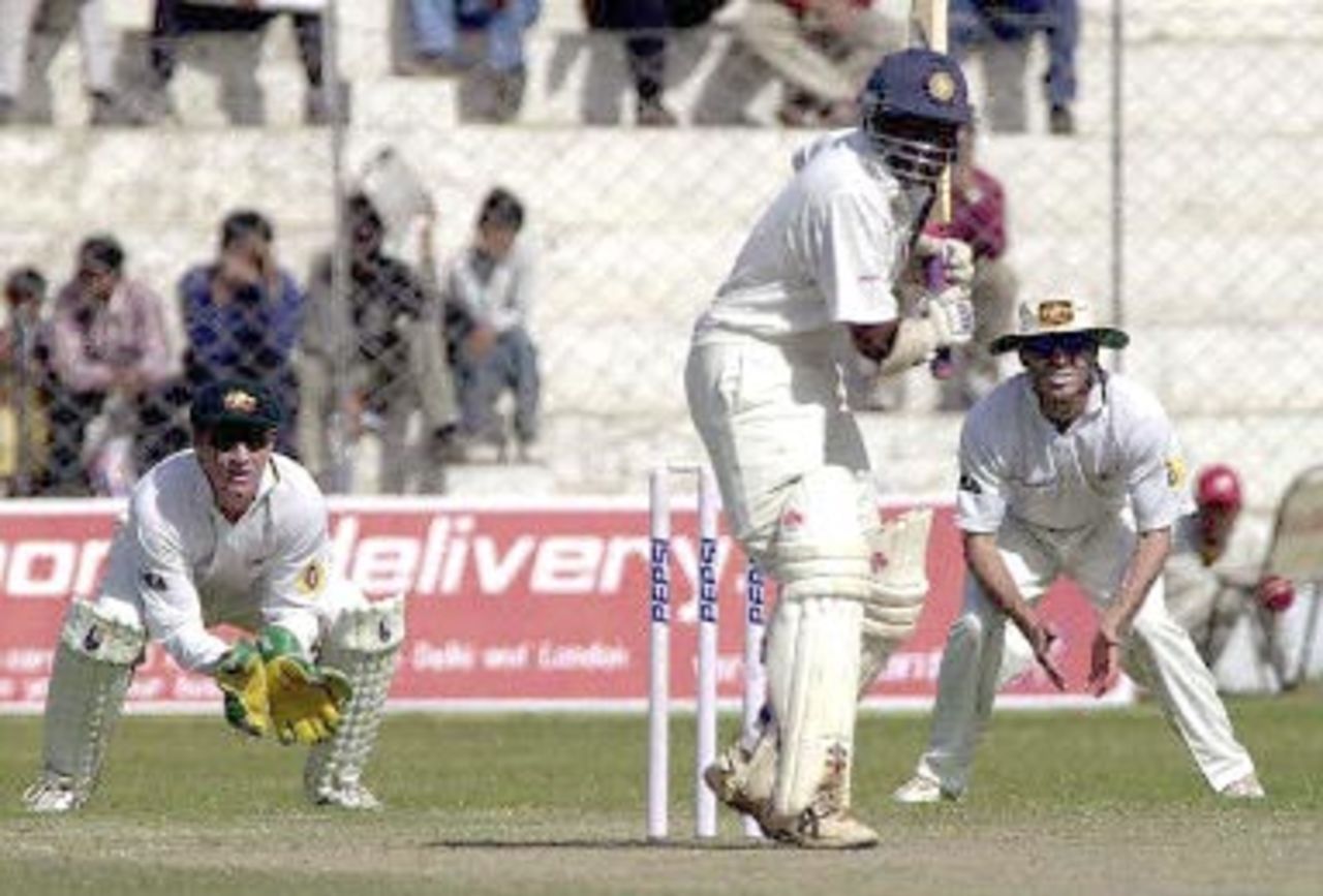 Board President's XI batsman Sridharan Sriram (C) hits a ball to the boundary as Austrlian wicketkeeper Brad Haddin (L) and fielder Shane Warne (R) look on during the second day's play of the second three-day match against Australia in New Delhi 07 March 2001. Australia scored 451 in their first innings.
