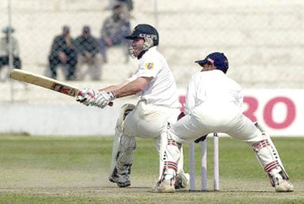 Australian batsman Damien Martyn hits a ball to the boundary as Indian wicketkeeper Vijay Dahiya (L) looks on during their second innings against the Board President's XI in New Delhi 08 March 2001. Australia scored 451 in their first innings with India at 221.