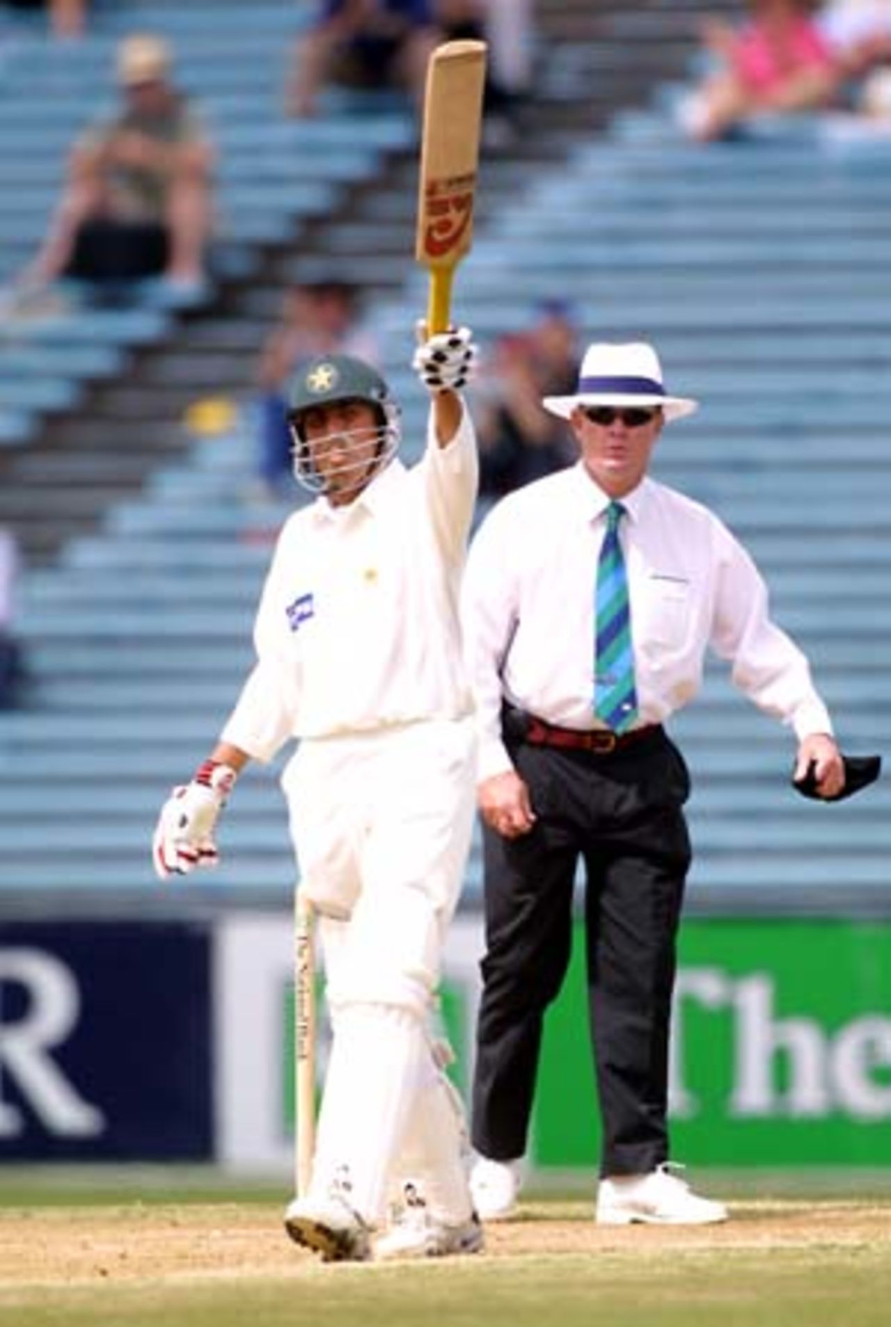 Pakistan batsman Younis Khan raises his bat in celebration of reaching 100 in his second innings, while umpire Russell Tiffin looks on. Younis went on to score 149 not out, his third Test century in his 10th Test. 1st Test: New Zealand v Pakistan at Eden Park, Auckland, 8-12 March 2001 (11 March 2001).