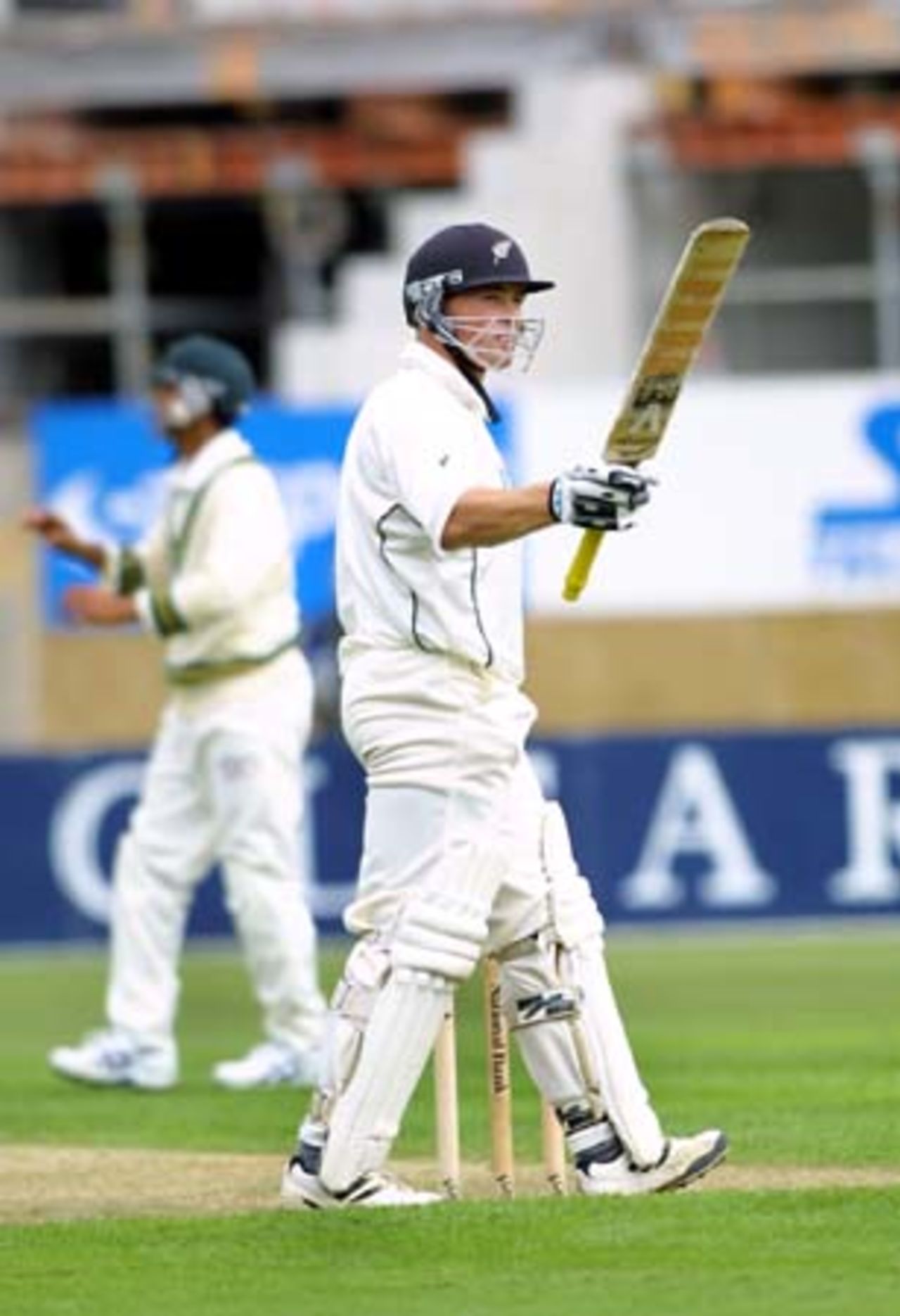 New Zealand opening batsman Matthew Bell raises his bat in celebration of reaching his second Test 50. Bell went on to score 75 in his first innings. Pakistan short leg fielder Faisal Iqbal receives the ball in the background. 2nd Test: New Zealand v Pakistan at Jade Stadium, Christchurch, 15-19 March 2001 (15 March 2001).