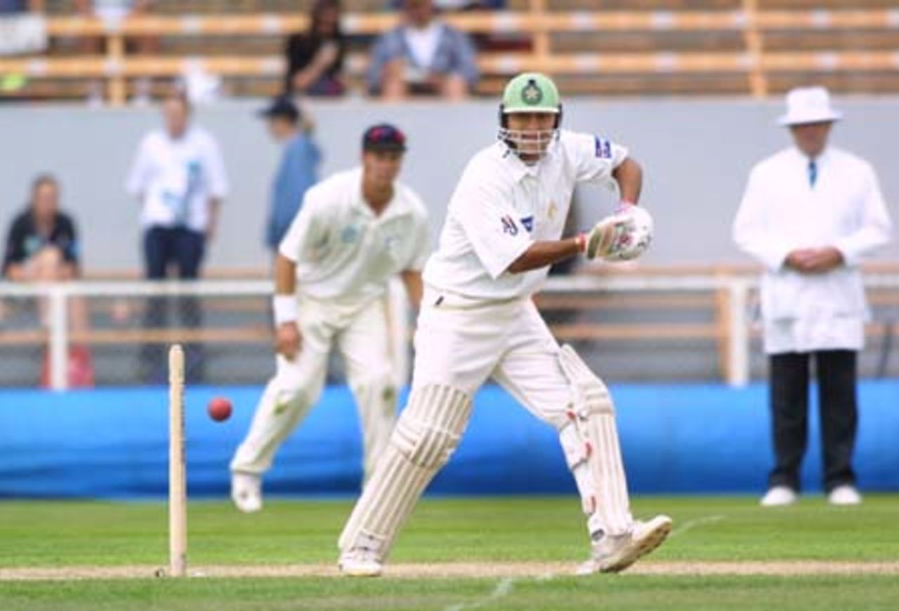 Pakistan batsman Faisal Iqbal square drives a ball during his first innings of 63 while New Zealand fielder Craig McMillan and umpire Daryl Harper look on in the background. 2nd Test: New Zealand v Pakistan at Jade Stadium, Christchurch, 15-19 March 2001 (17 March 2001).