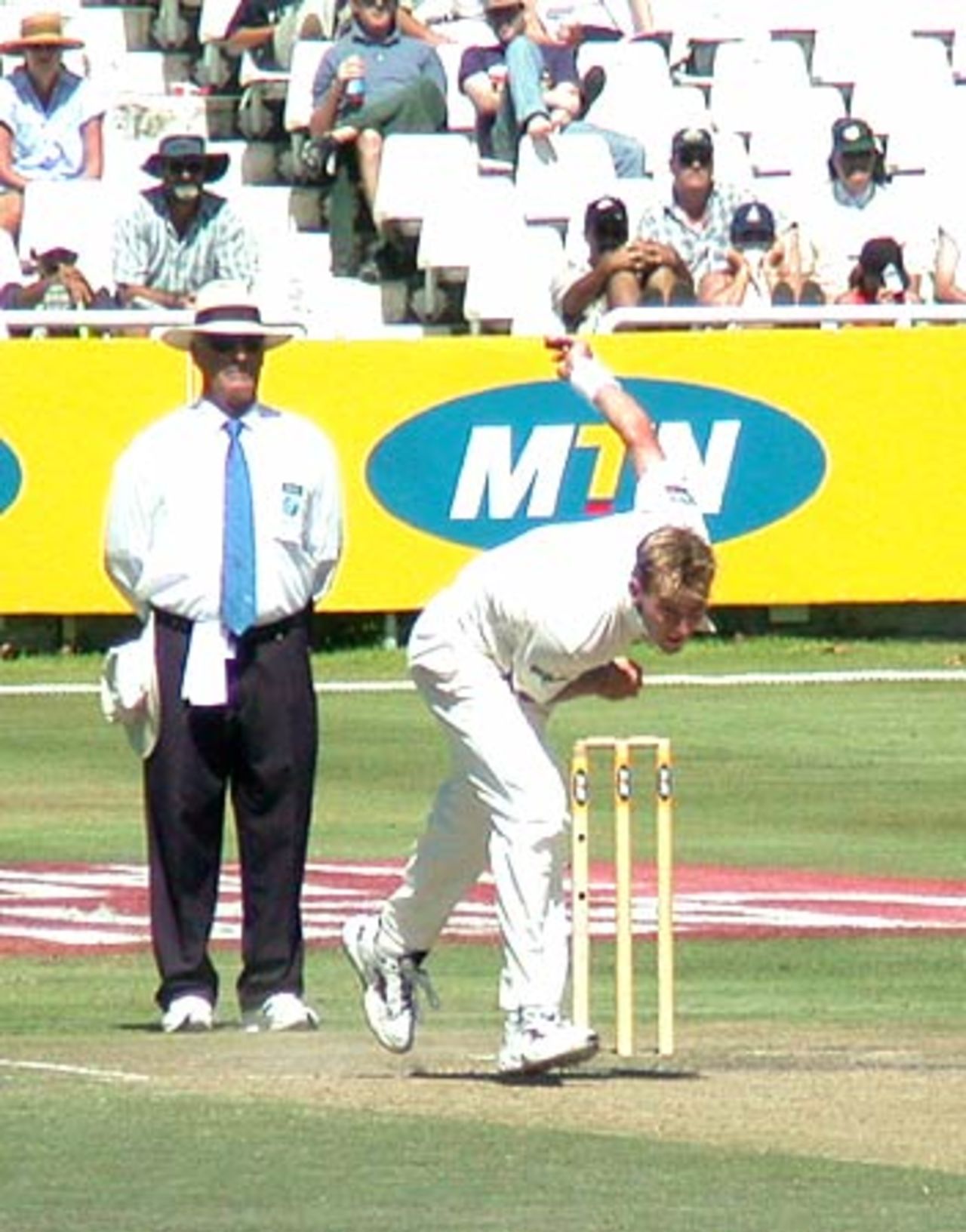 Brett Lee in full flight while umpire Rudi Koertzen looks on