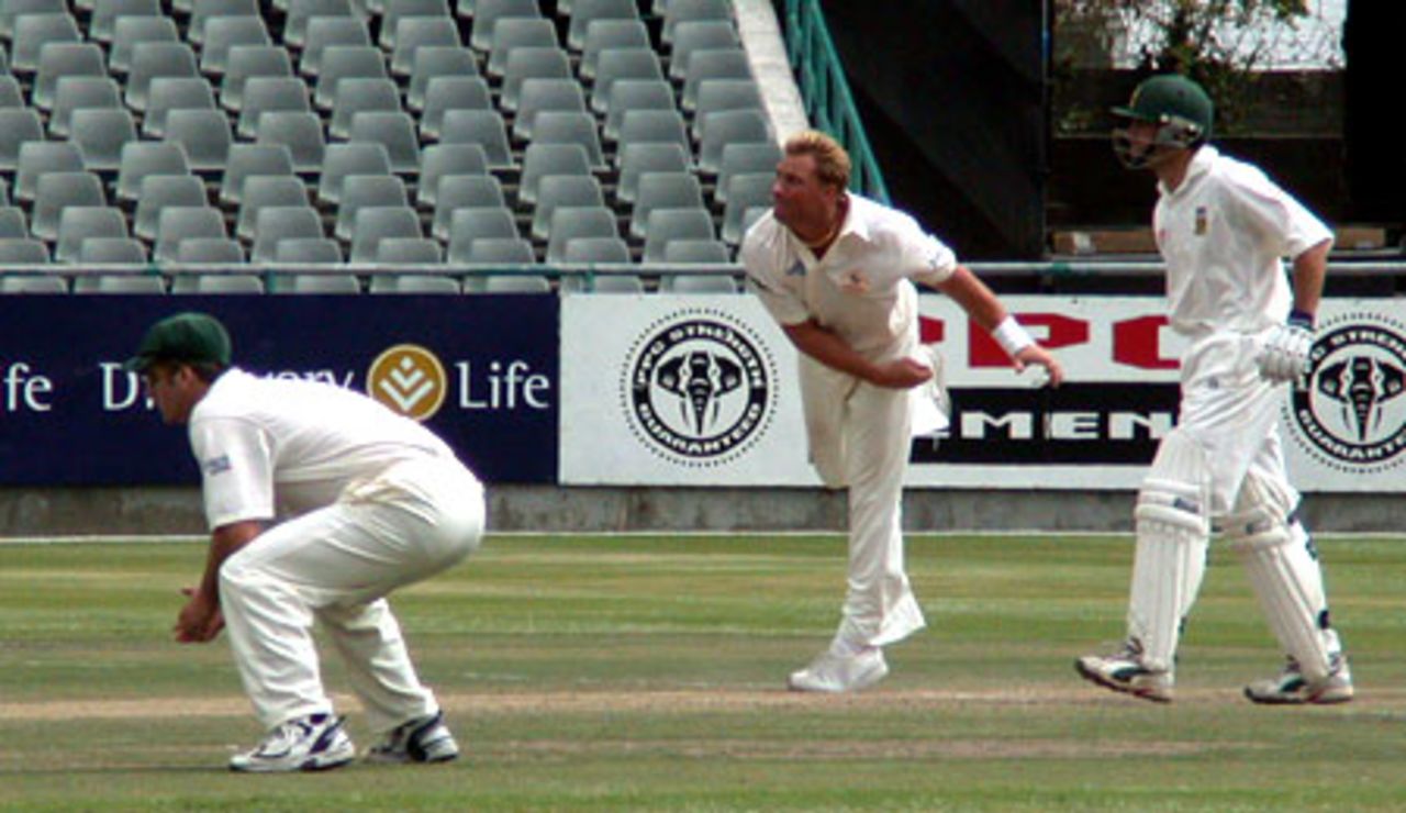 Shane Warne sends down a delivery while captain Steve Waugh and SA's Neil McKenzie looks on
