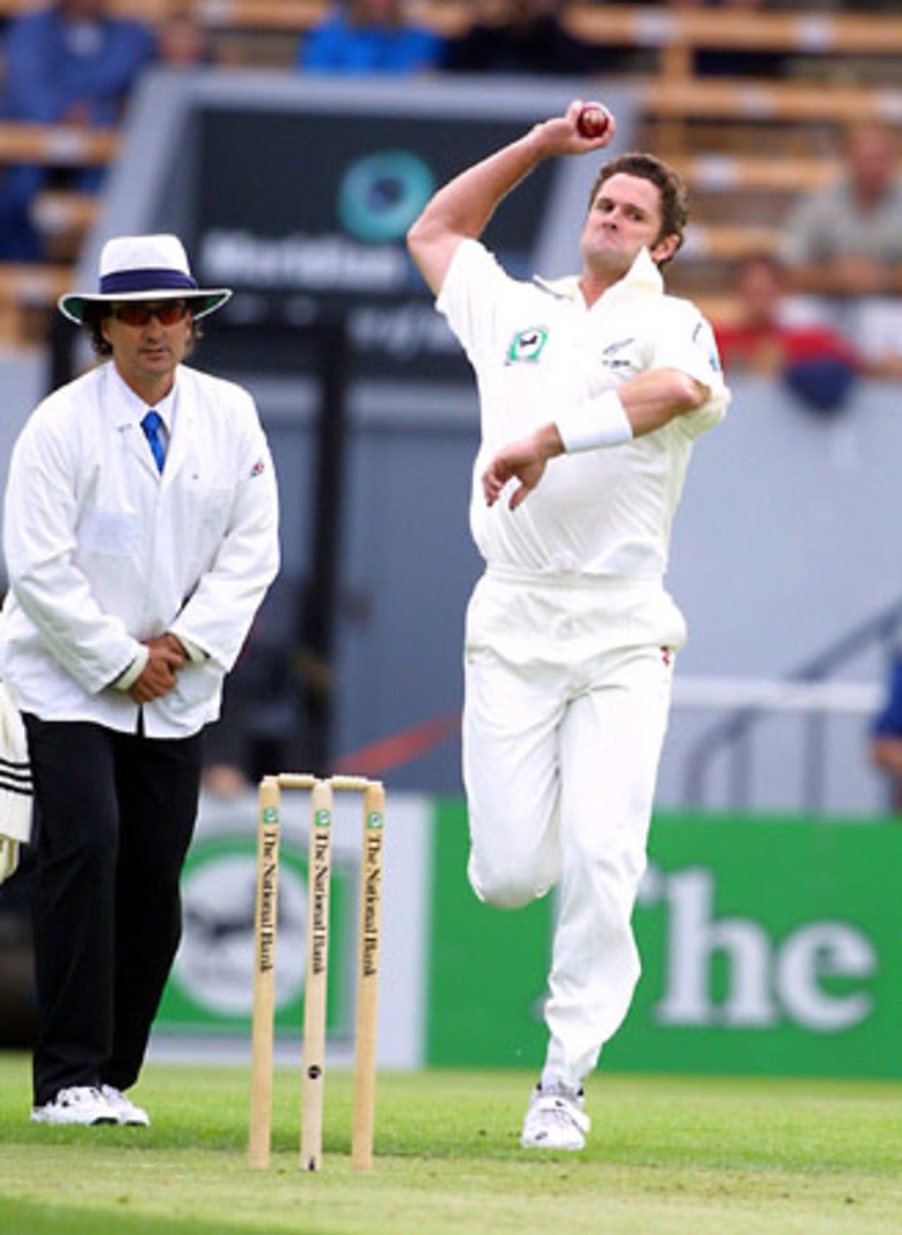 New Zealand bowler Chris Cairns delivers a ball during his first innings spell of 3-58 from 15 overs while umpire Brent Bowden looks on. 1st Test: New Zealand v England at Jade Stadium, Christchurch, 13-17 March 2002 (13 March 2002).