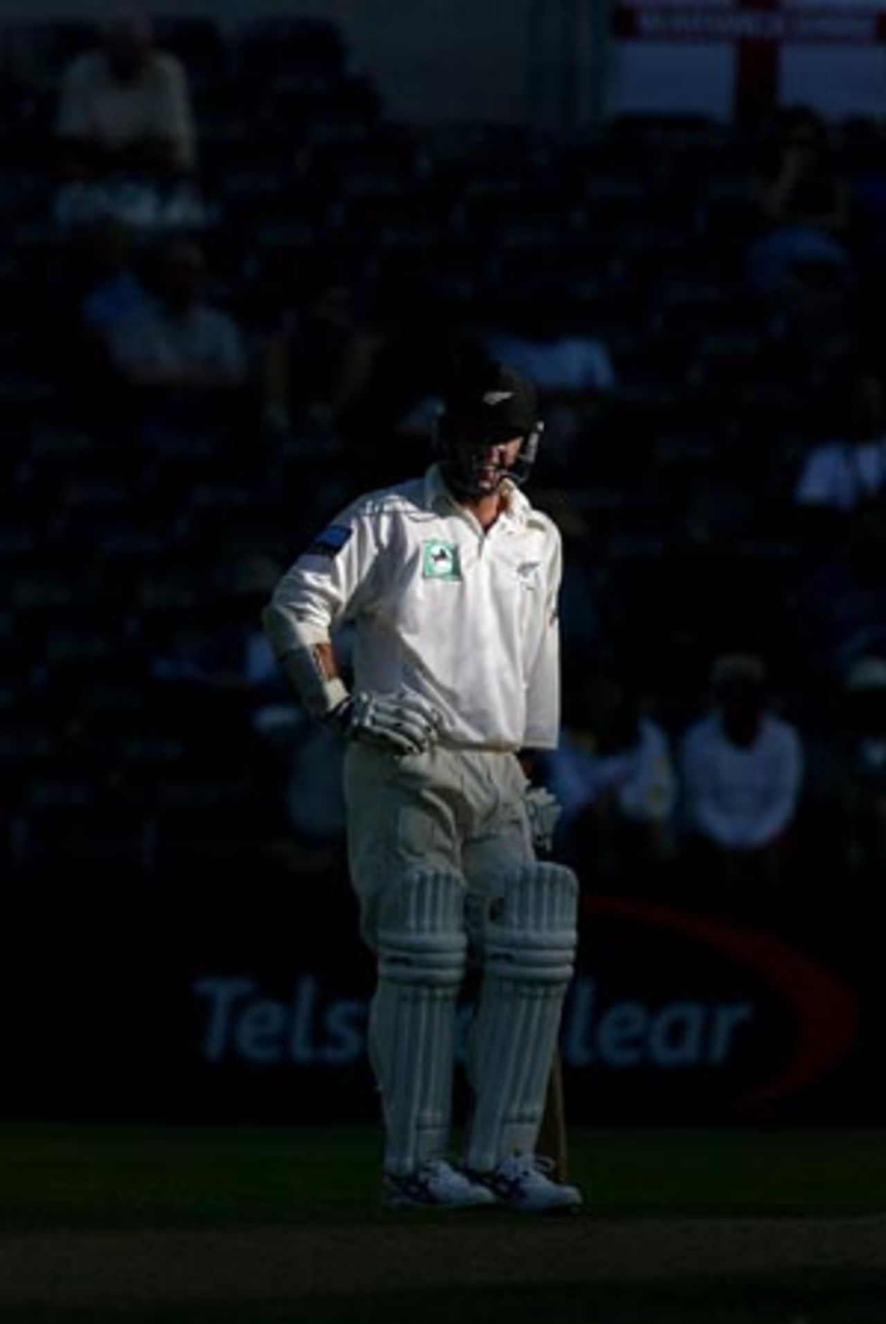 New Zealand batsman Mark Richardson stands in the shadow cast by the new West Stand late on the third day as umpires discuss the light conditions. Play was subsequently called off due to bad light. 1st Test: New Zealand v England at Jade Stadium, Christchurch, 13-17 March 2002 (15 March 2002).