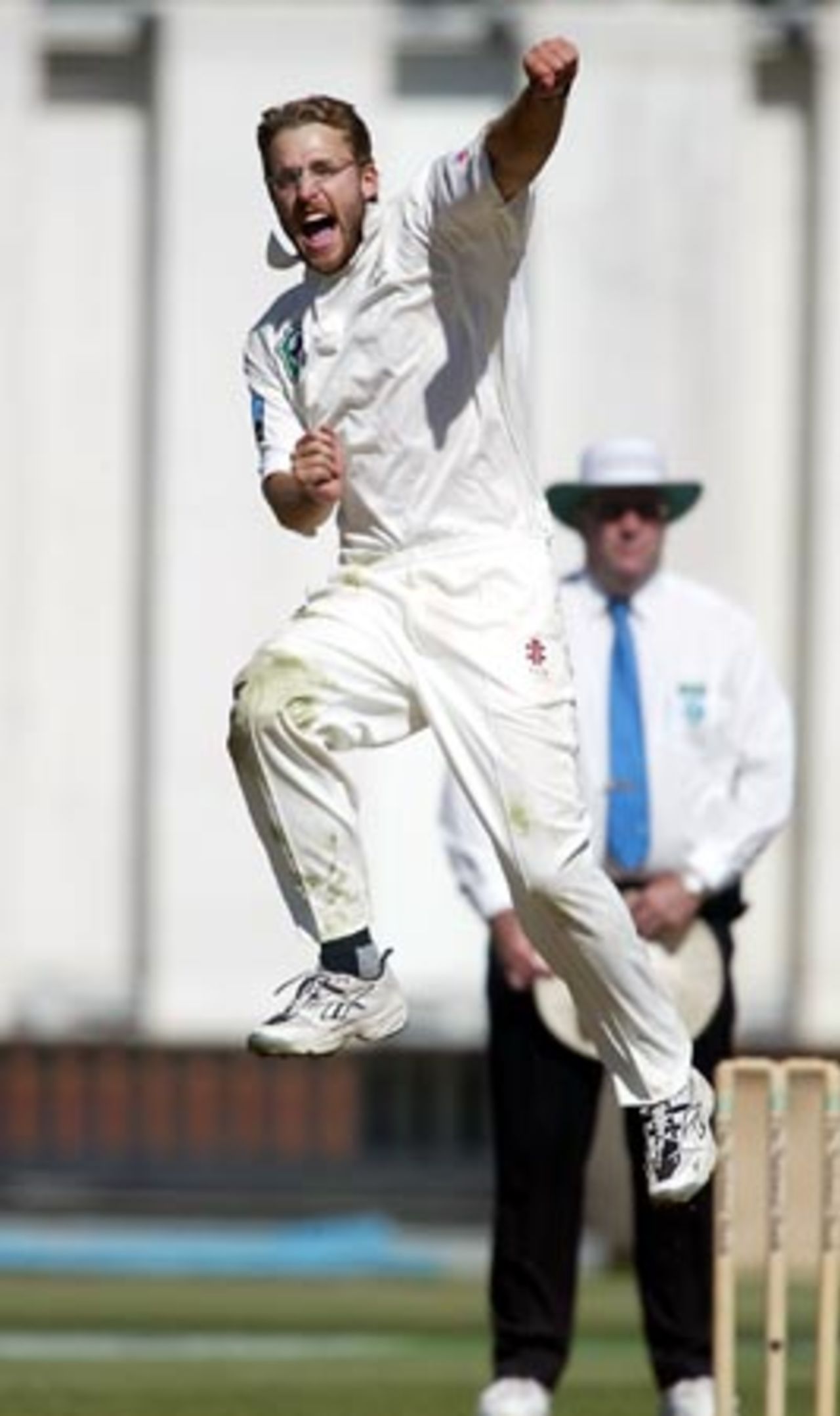 New Zealand bowler Daniel Vettori punches the air as he jumps to celebrate the dismissal of England batsman Nasser Hussain, caught by Nathan Astle for 66 in his first innings. Umpire Darrell Hair from Australia looks on in the background. 2nd Test: New Zealand v England at Basin Reserve, Wellington, 21-25 March 2002 (22 March 2002).
