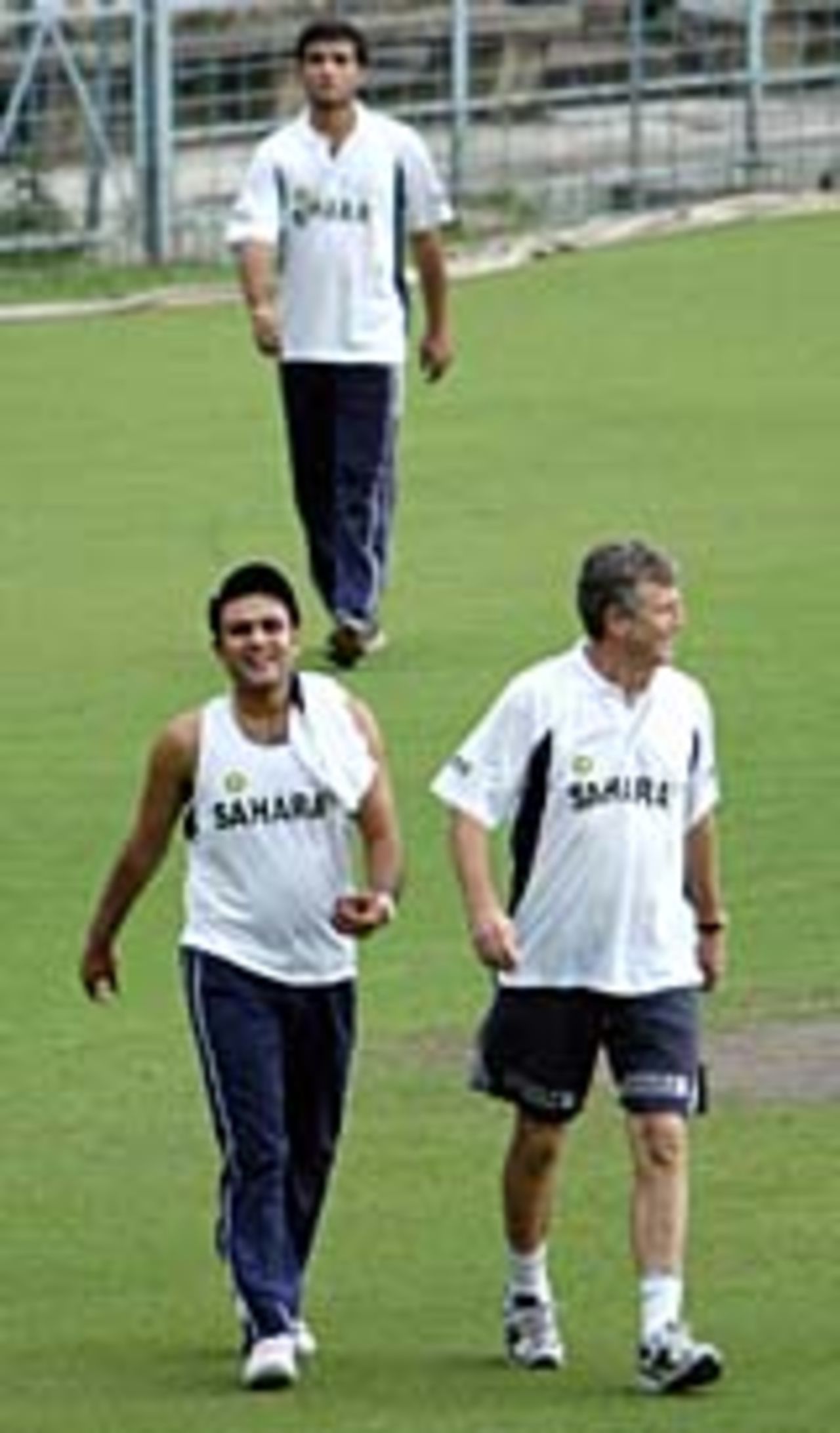 Virender Sehwag and India's coach John Wright share a light moment as they walk ahead of team captain Sourav Ganguly (C) following an indoor physical training session during the first day of a conditioning camp at Eden Gardens, March 7, 2004