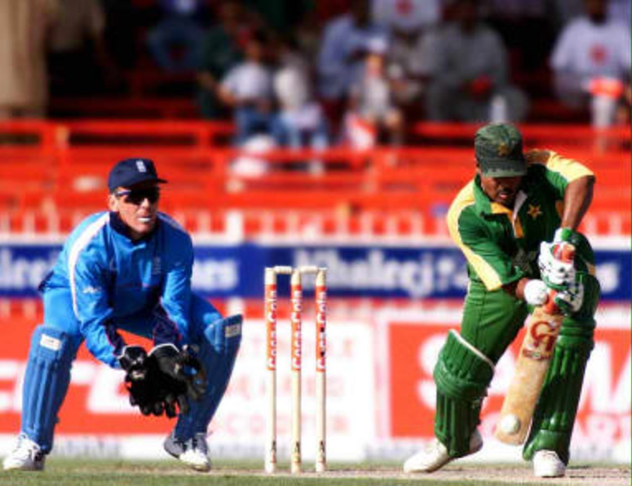 Ijaz Ahmed leans forward to middle the ball while being watched carefully by England skipper and wicketkeeper, Alec Stewart, on 7th April 1999 at Sharjah in the Coca Cola Cup.