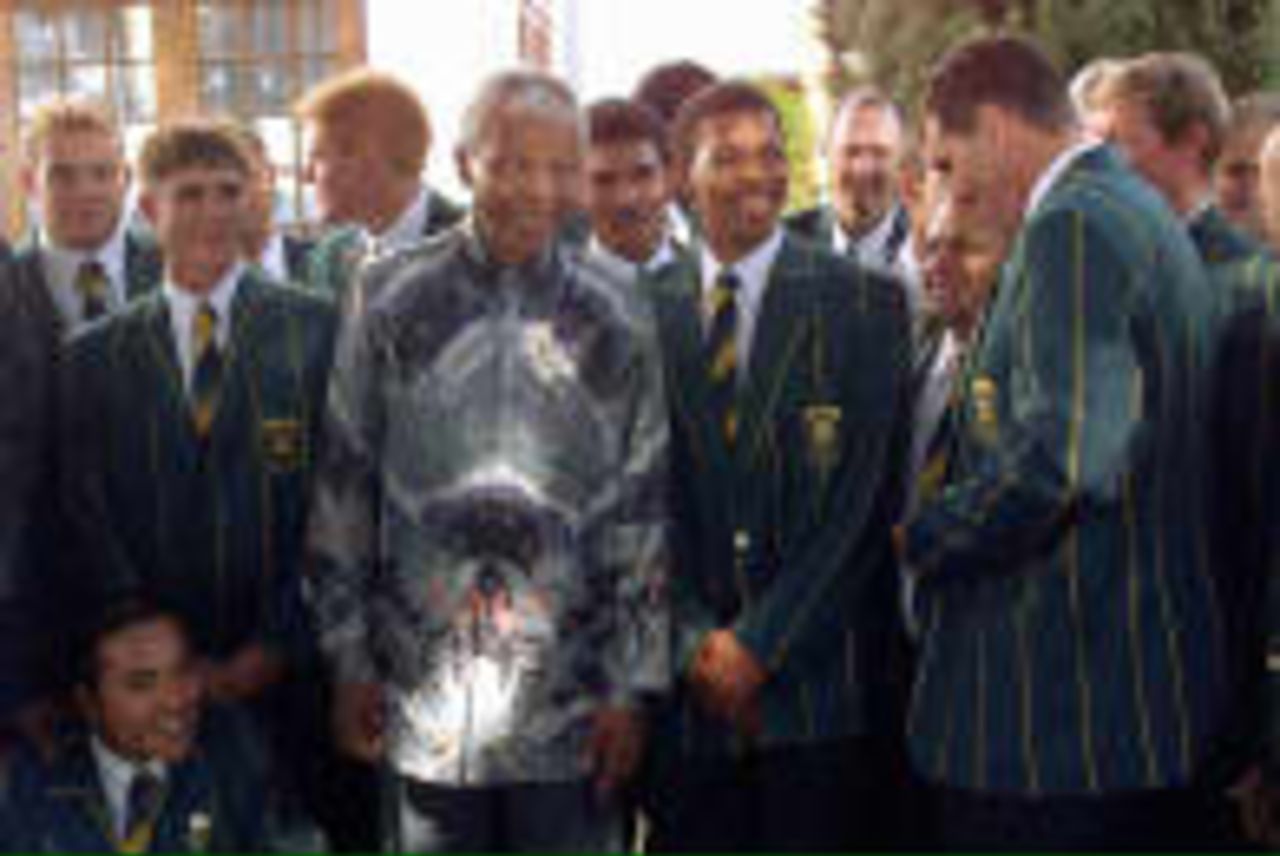South  African President Nelson Mandela jokes 15 April 1999 in Pretoria with South African cricket captain Hansie Cronje watched by other players outside Mandela's official residence. Mandela hosted a lunch for the national cricket team to boost their moral before the upcoming cricket world cup in England.