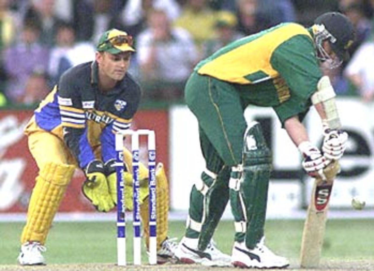 South African batsman Lance Klusener puts down a fast ball while defending the wickets, and Australian wicket keeper Adam Gilchrist looks on 16 April 2000 during the third one-day match against South Africa at the Wanderers Cricket stadium in Johannesburg.