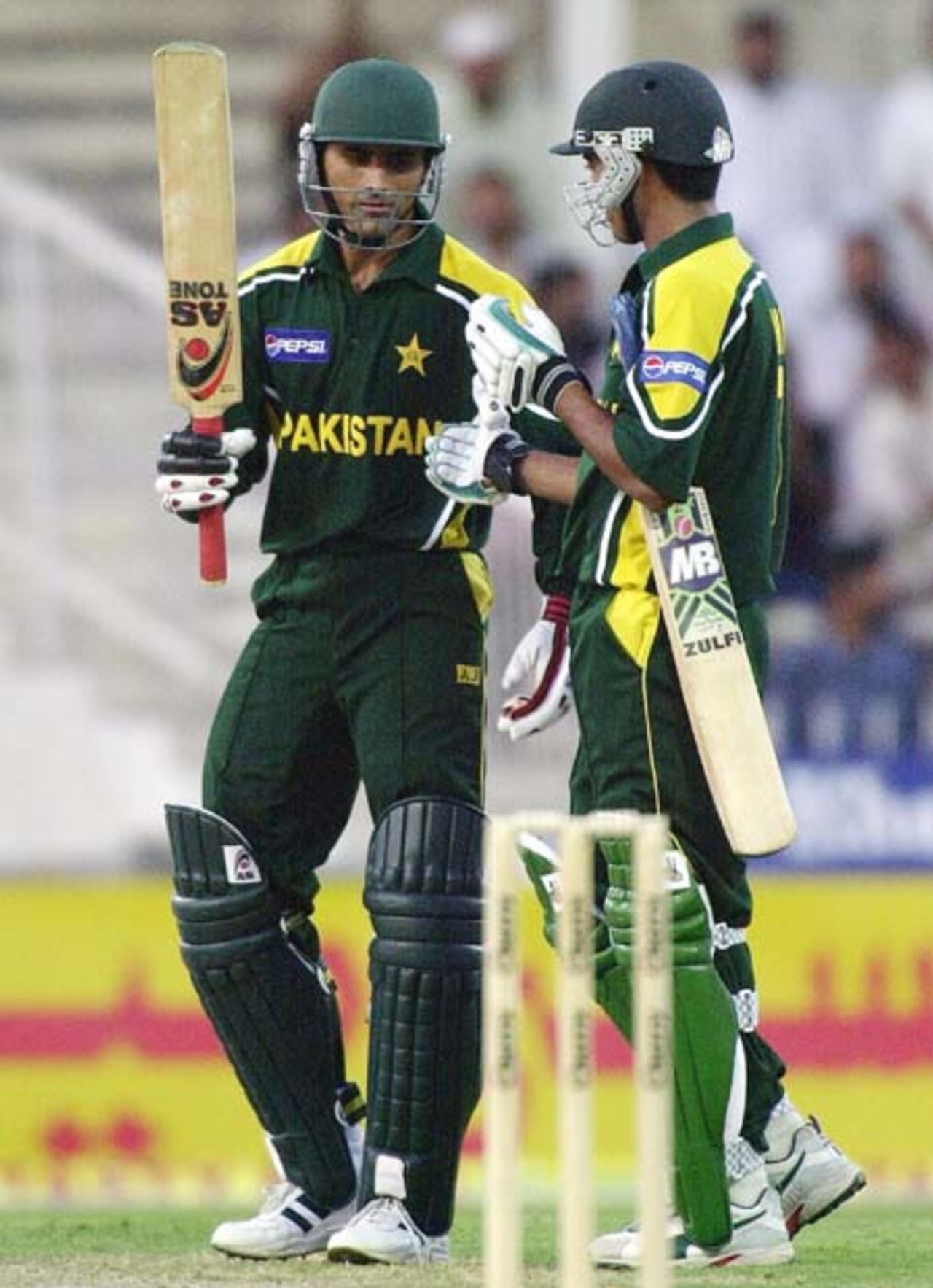 Pakistani all-rounder Abdul Razzaq (L) celeberates his half century with his team mate Mohammad Sami during his 76 runs inning in the first one day match against Zimbabwe in Sharjah, 03 April 2003.