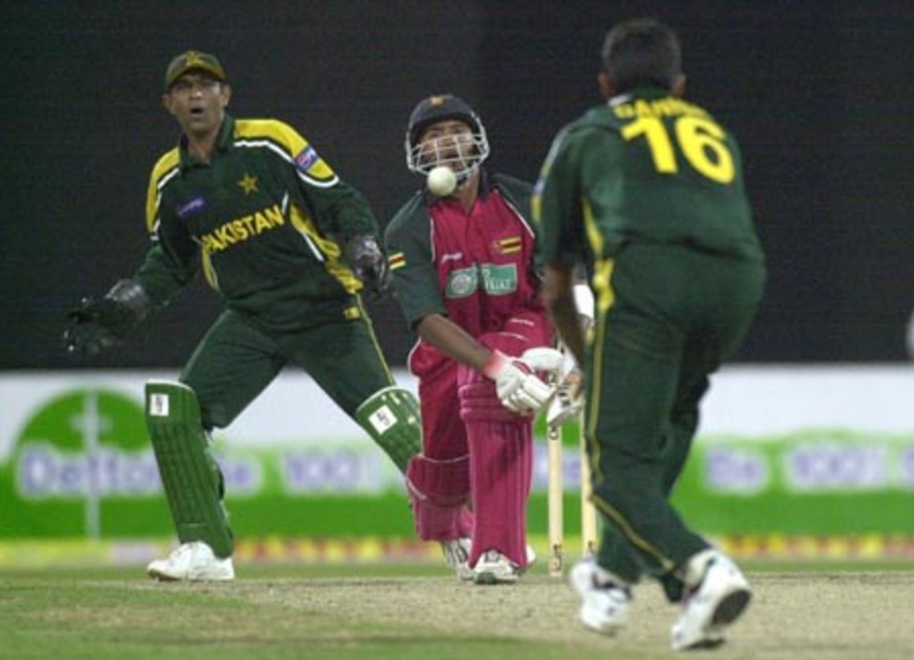 Zimbabwe batsman Dion Ebrahim (C) watches a ball delivered by Pakistani spinner Danish Kaneria (R) during the first one day match of the four nation Sharjah Cricket tournament, 03 April 2003.