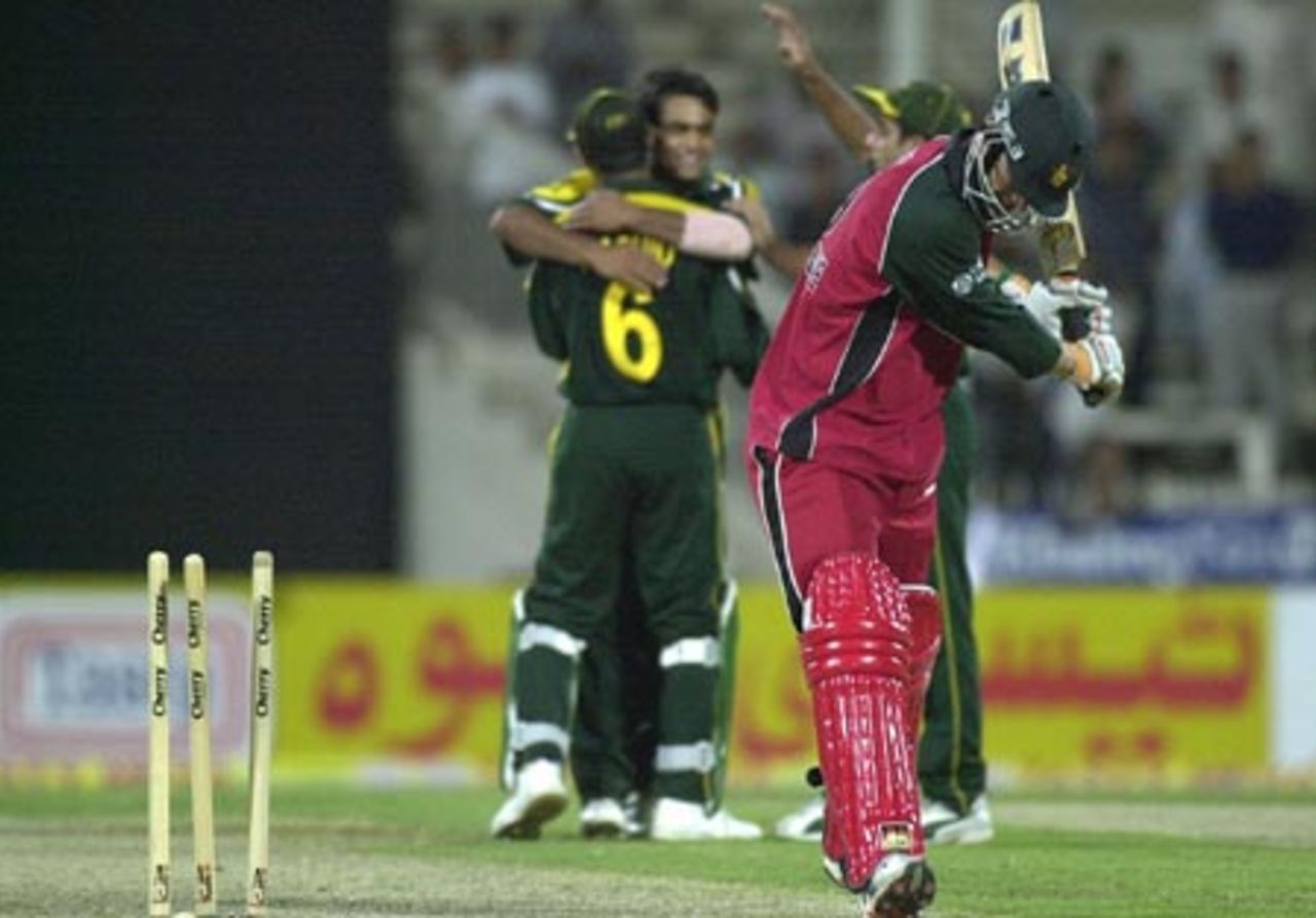 Pakistani spinner Mohammad Hafeez (C) celebrates his  2nd victim as Zambabwe's dejected batsman Andy Blignaut (R) leaves the crease during the first one-day match of the four-nation Sharjah cricket tournament 03 April 2003.
