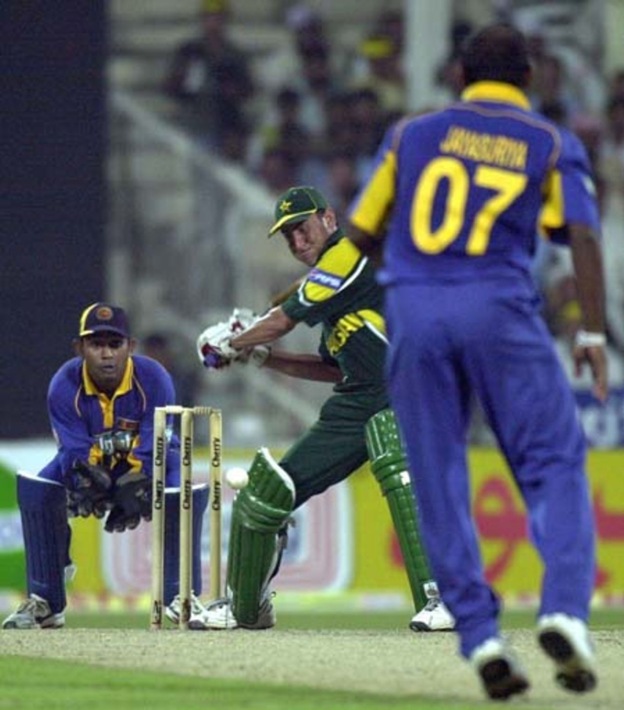 Pakistani key batsman Younis Khan (C) drives for a boundary off Sri Lankan spinner Sanath Jayasuriya as wicket keeper Prasanna Jayawardene (L) looks on during the 2nd one day match of the Four Nation Sharjah Cricket Tournament, 04 April 2003.