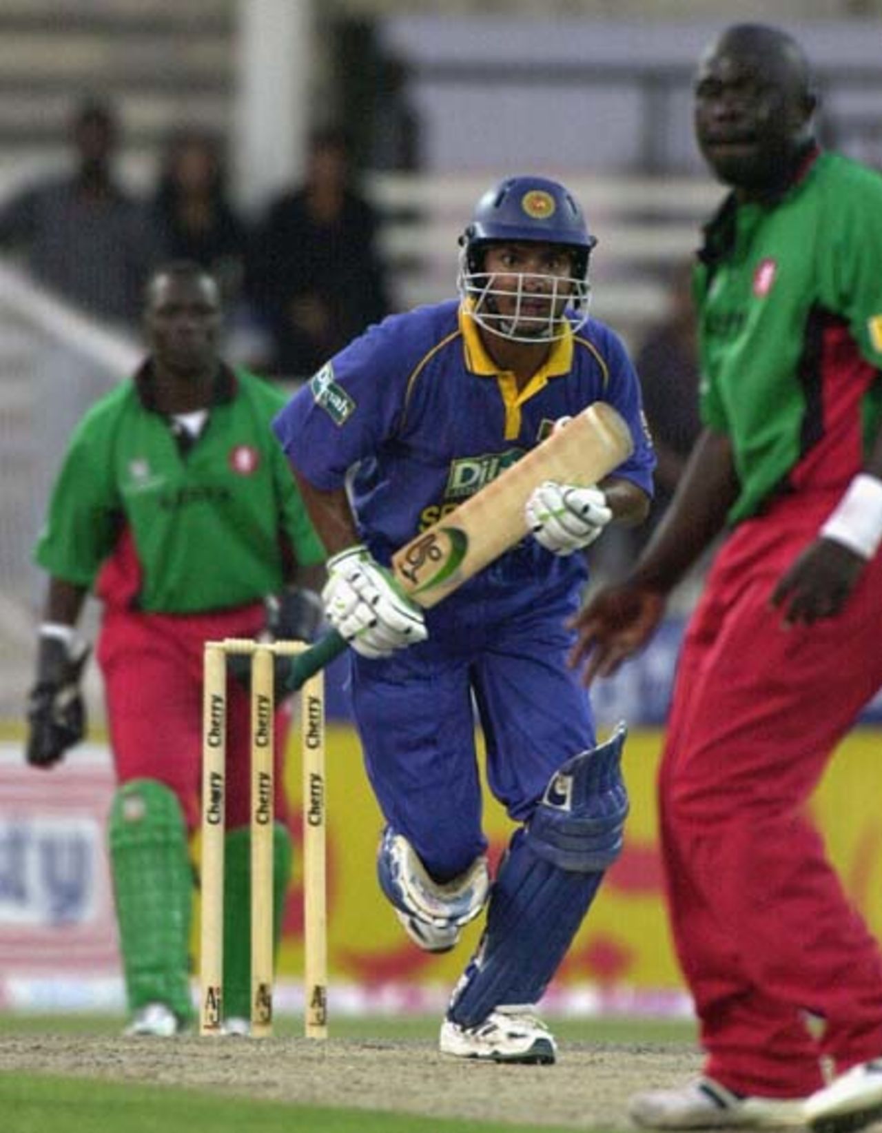 Sri Lanka's Kumar Sangakkara (C) rushes to complete his 2nd century of the tournament as Kenyan pacer Thomos Odoyo (R) watches the ball during the 4th one-day match in the Four Nation Sharjah Cricket Tournament, 06 April 2003.
