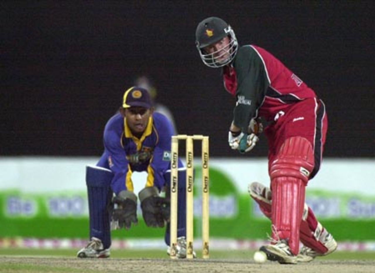Zimbabwe's top scorer Grant Flower (R) plays during his decisive 61 runs innings as Sri Lankan wicketkeeper Prasanna Jayawardene looks on during the fifth one-day match in the Four Nation Sharjah Cricket Tournament, 07 April 2003.