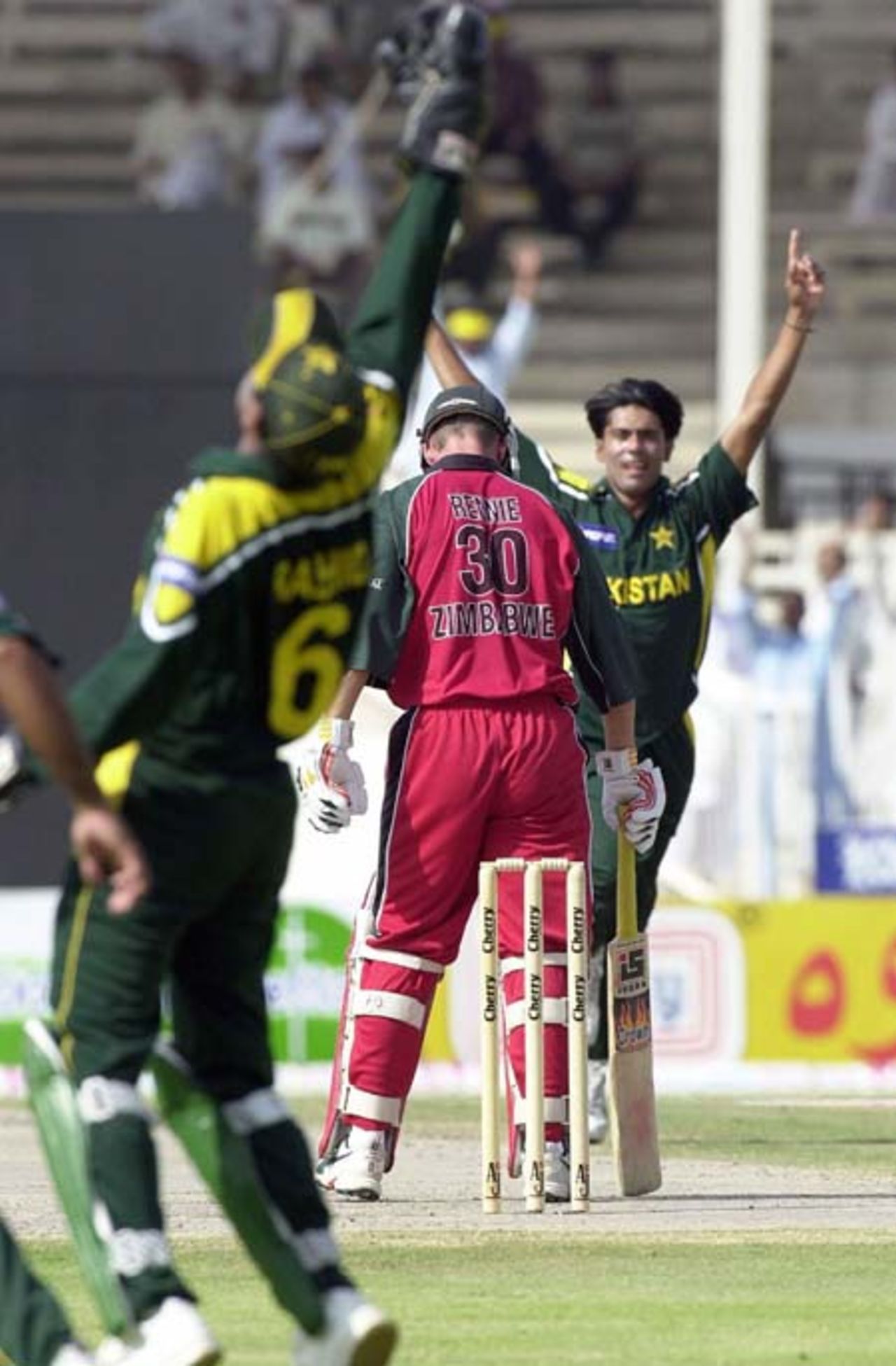 Pakistani wicketkeeper and captain Rashid Latif (L) celebrates his catch of Zimbabwe batsman Gavin Rennie (C) on the bowling of Mohammad Sami celebrates his third wicket during the final match of the Four Nation Sharjah Cricket Tournament, 10 April 2003.