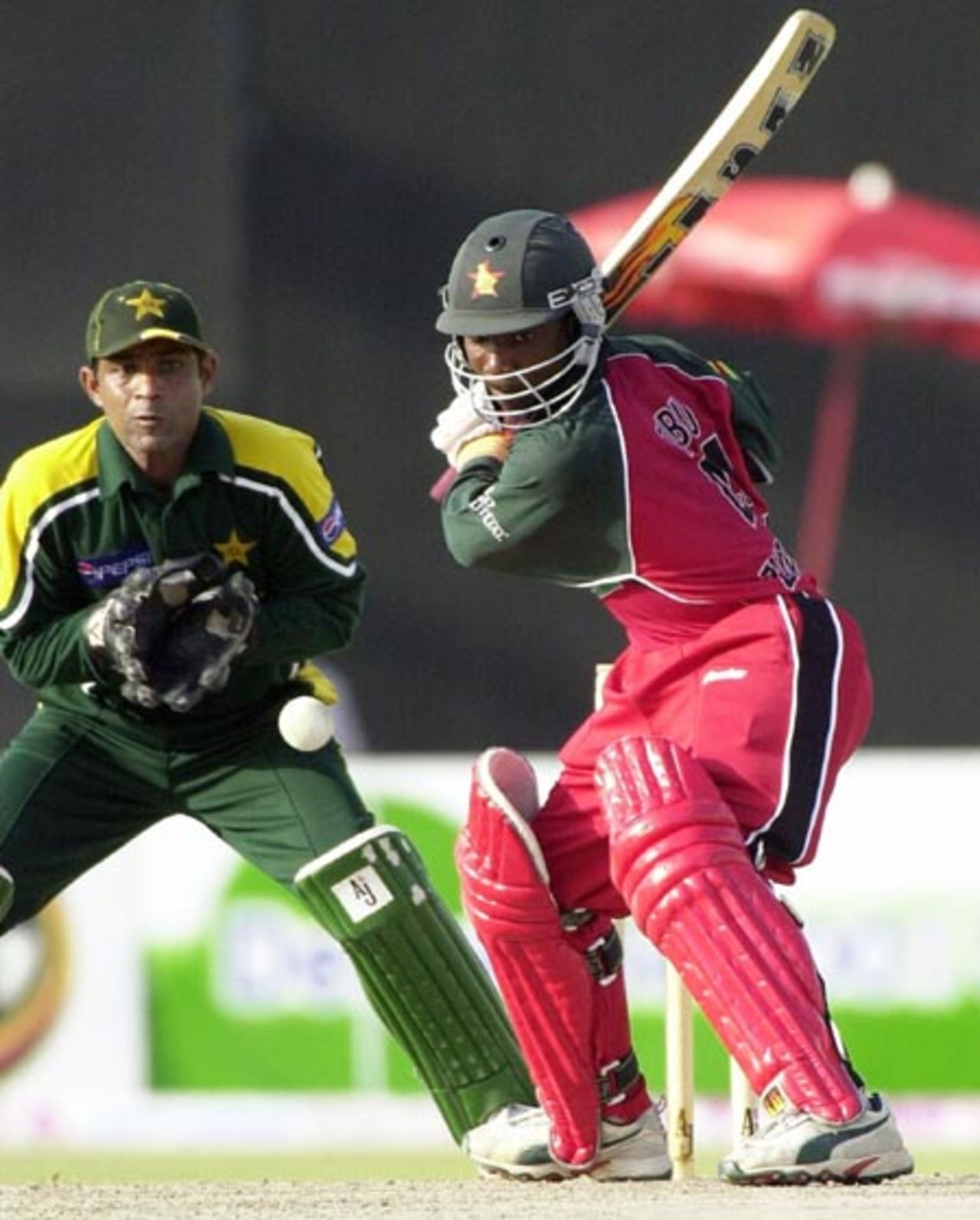 Zimbabwe top scorer Tatenda Taibu (R) drives for a boundary during his brilliant unbeaten 74 runs inning as Pakistan wicketkeeper Rashid Latif looks on during the final of the Four Nation Sharjah Cricket Tournament, 10 April 2003.
