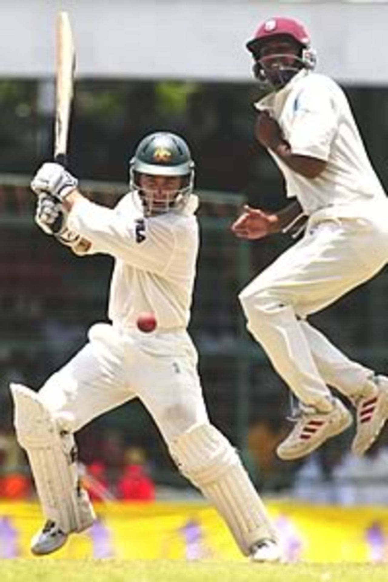 Justin Langer of Australia hits out as Darren Ganga of the West Indies jumps clear during day two of the 1st Test between the West Indies and Australia played at Bourda Oval, Georgetown, Guyana, on April 11, 2003.