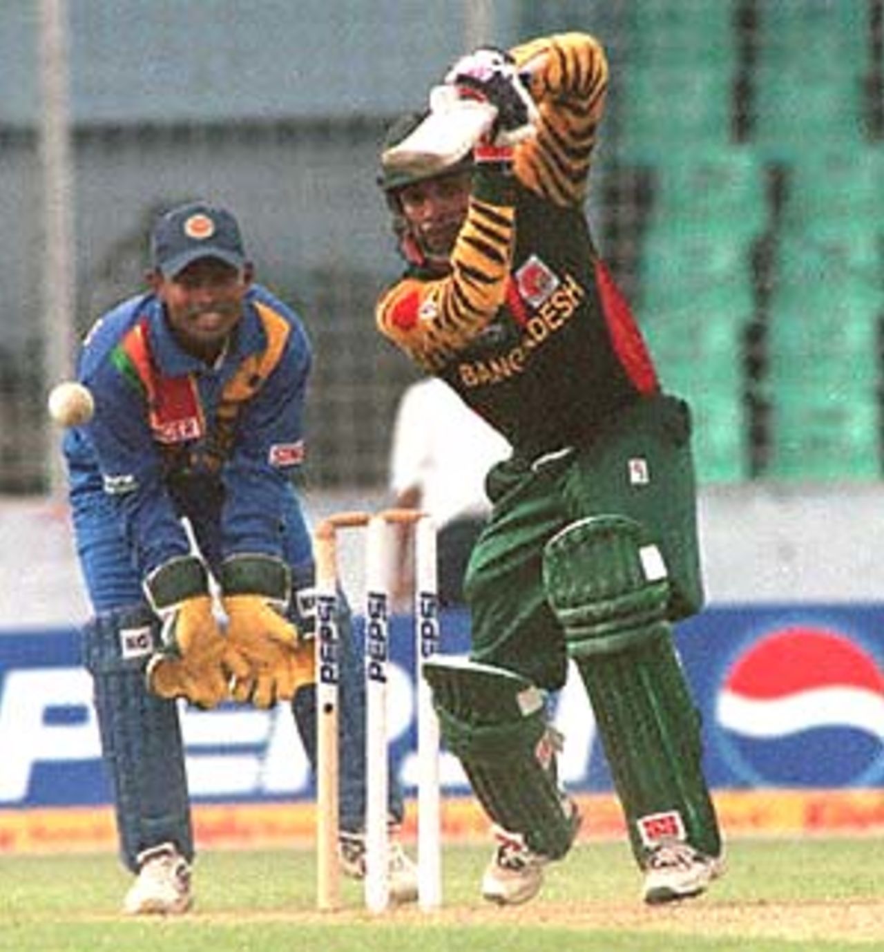 Bangladesh opener Javed Omar drives on his way to an unbeaten 85 against Sri Lanka in the opening match of the four-nation Asia Cup limited-overs tournament at the Bangabandhu national stadium in Dhaka 29 May 2000. Sri Lankan wicket-keeper Romesh Kaluwitharana waits with open gloves. India and Pakistan are the other teams in the tournament to determine the regional one-day champions. Bangladesh v Sri Lanka, Asia Cup, 1999/00, Bangabandhu National Stadium, Dhaka 29 May 2000.