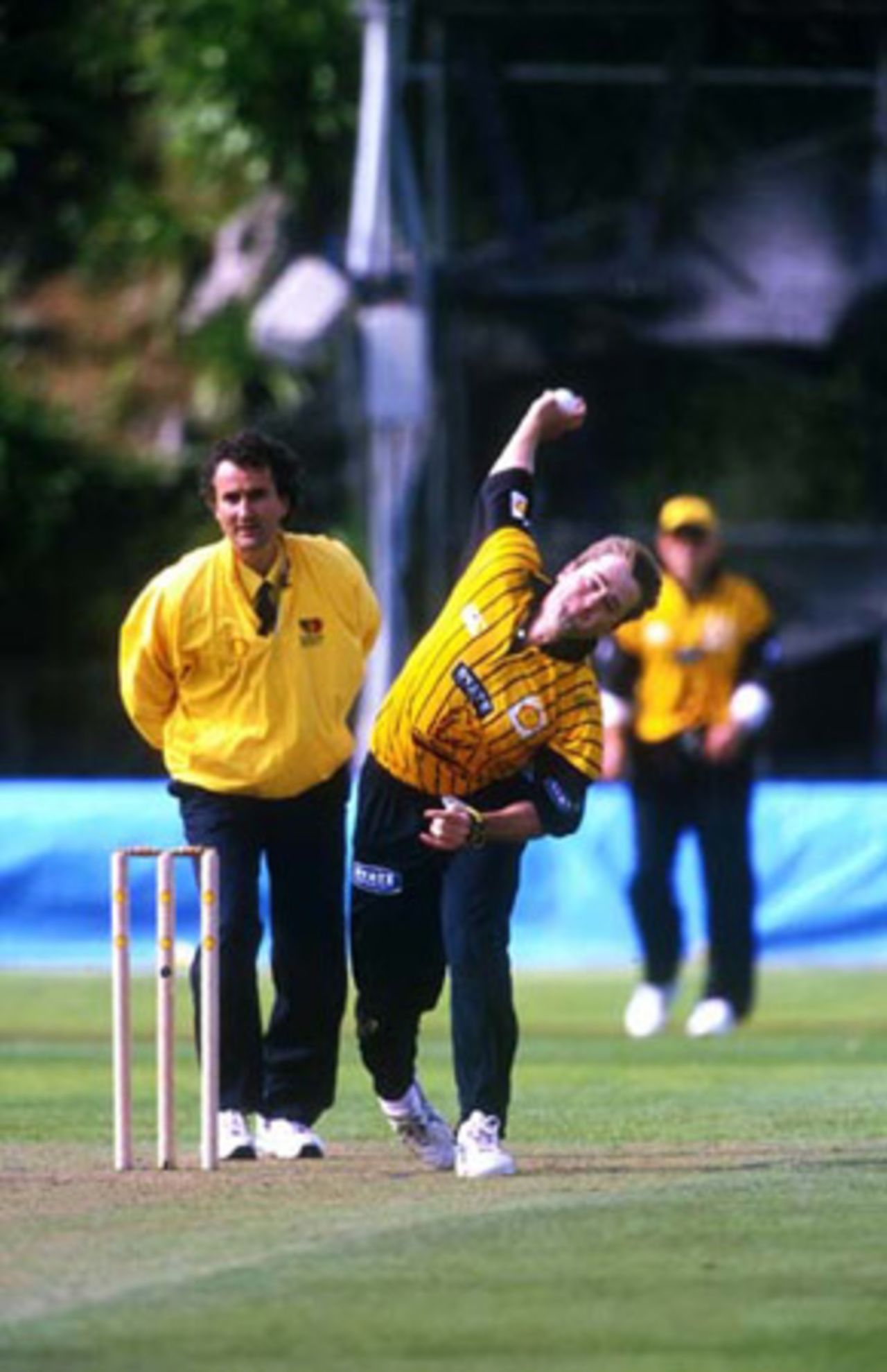 Wellington bowler Paul Hitchcock delivers a ball during his spell of 1-41 from 10 overs while umpire Brent Bowden looks on. Shell Cup: Auckland v Wellington at Eden Park Outer Oval, Auckland, 27 December 2000.
