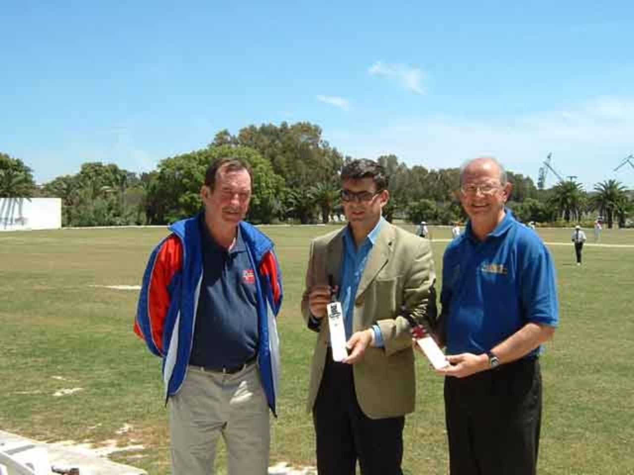 Bob Gibb (left) presents Maltese Sports Minister Jesmond Mugliett (centre) and Malta Cricket Association Chairman Pierre Naudi (right) with mini bats