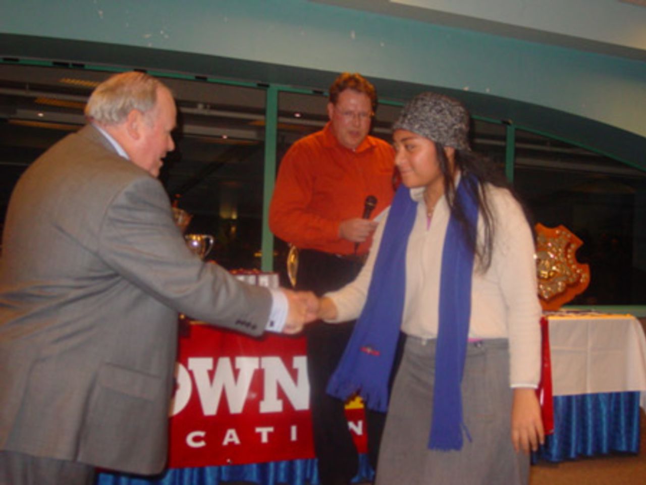 Eden Roskill women's player Antonia Tuala-Lili (right) receives the Robinson Cup for the best first year player in women's first grade cricket from Auckland Cricket Association president Ray Hopkins. Awards announcer and Auckland Cricket Association club cricket manager Chris Lander looks on in the background. Crown Relocations Auckland Association club prizegiving evening, West Stand, Eden Park, Auckland, 13 May 2003.