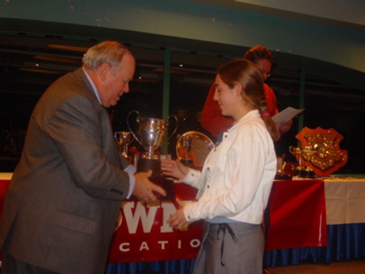 Cornwall women's player Amy Hodgson (right) receives the McKenzie Cup for most improved women's first grade player and the Duncan Rae Cup for most wickets in women's first grade from Auckland Cricket Association president Ray Hopkins. Crown Relocations Auckland Association club prizegiving evening, West Stand, Eden Park, Auckland, 13 May 2003.