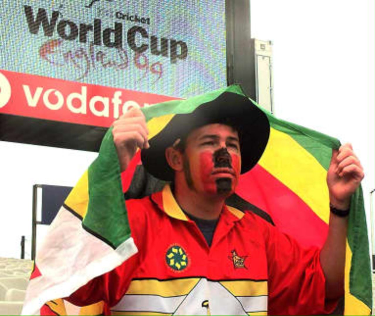 A Zimbabwe cricket supporter shelters from rain at Headingley 07 June 1999. The rain held up play between Zimbabwe and New Zealand for the second day in a row