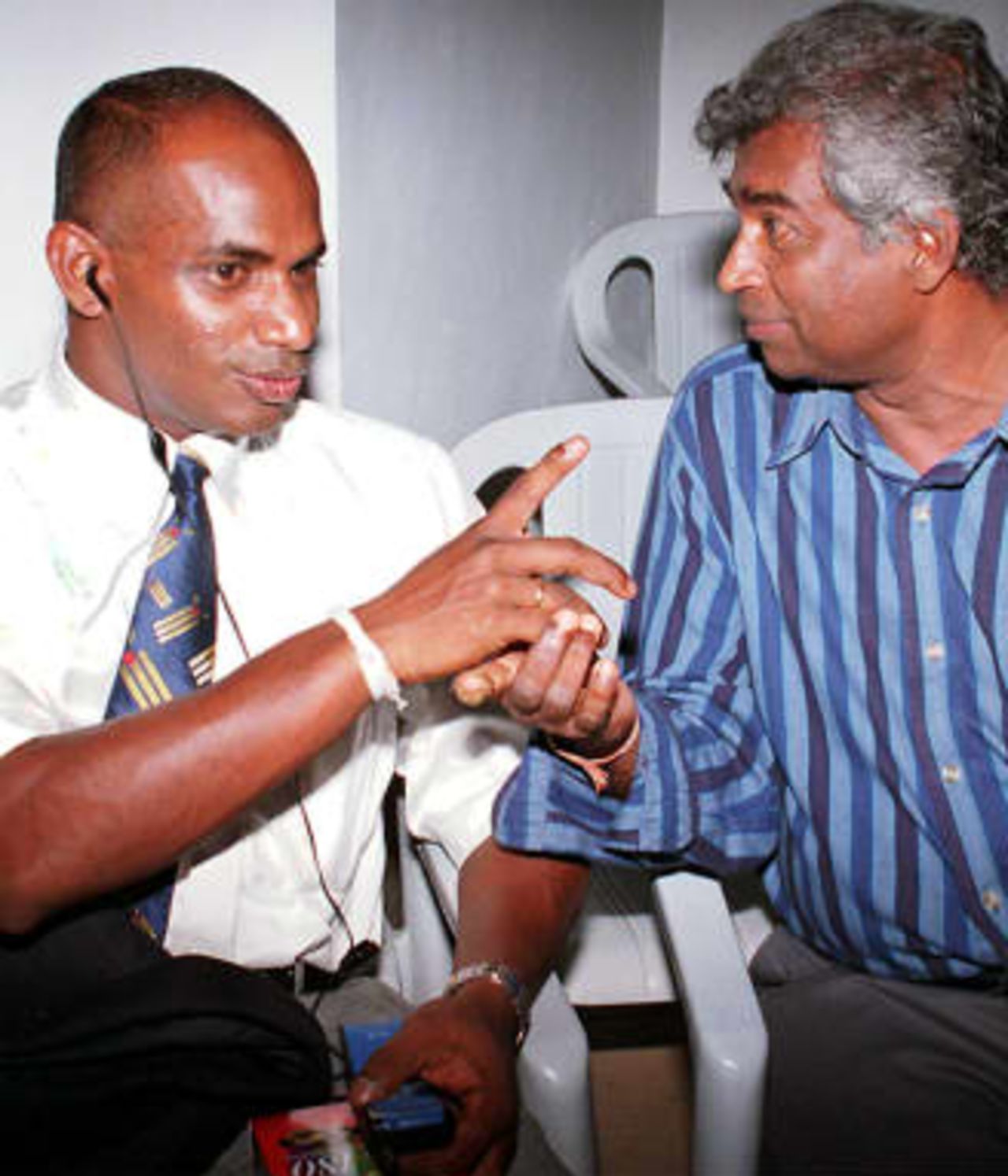 Sri Lanka's former master blaster Sanath Jayasuriya (L) wears the earphone of a cellular telephone as he speaks with top local cricket commentator Palitha Perera 24 April 1999 just before the Sri Lankan team left for England to defend the country's cricket world cup. The team was knocked out of the first round itself and officials blame mobile phones and wives for the downfall of players. Perera has called for a shakeup of the team