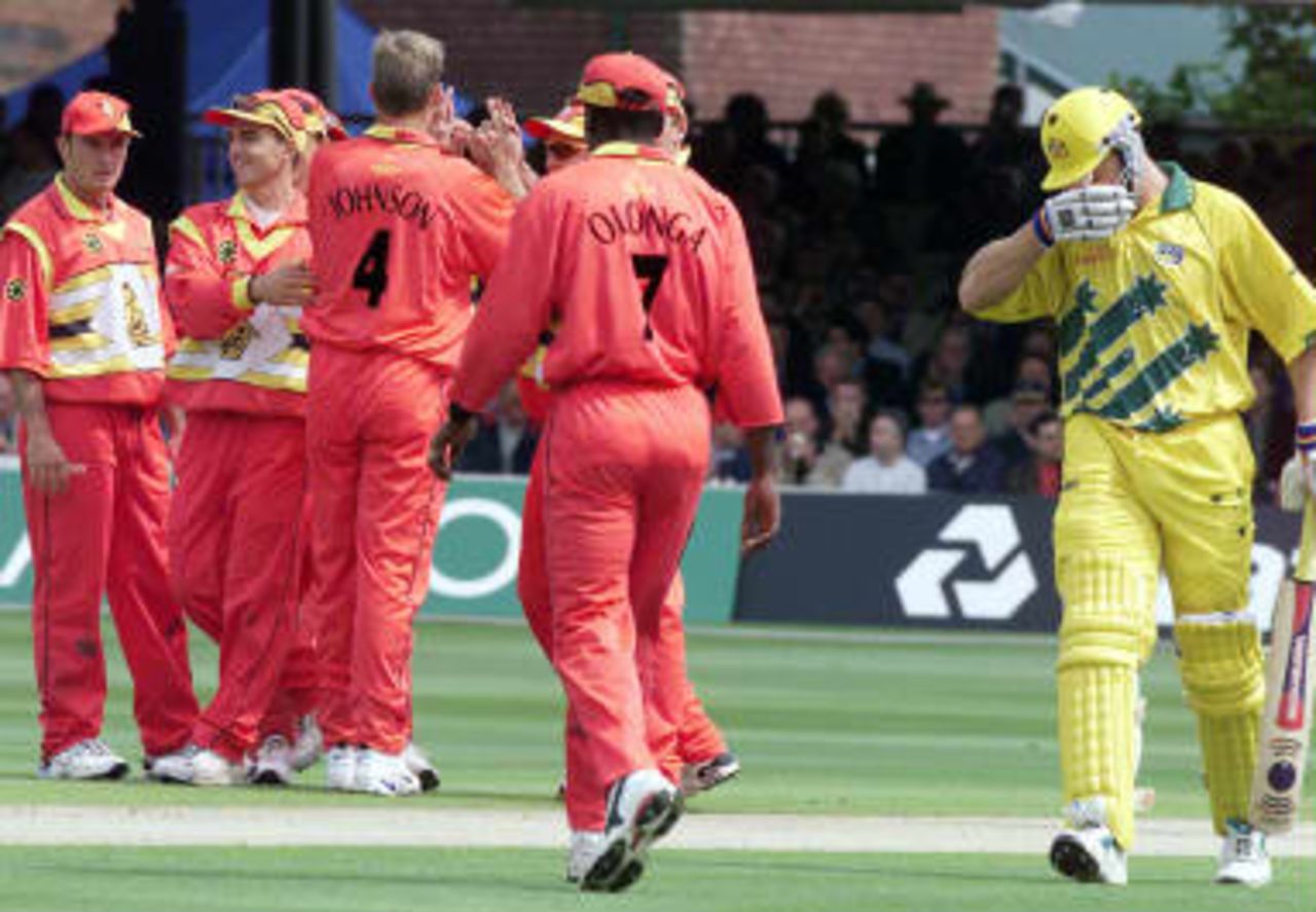 Australia`s Adam Gilchrist walks past the celebrating Zimbabwe team after he was  lbw