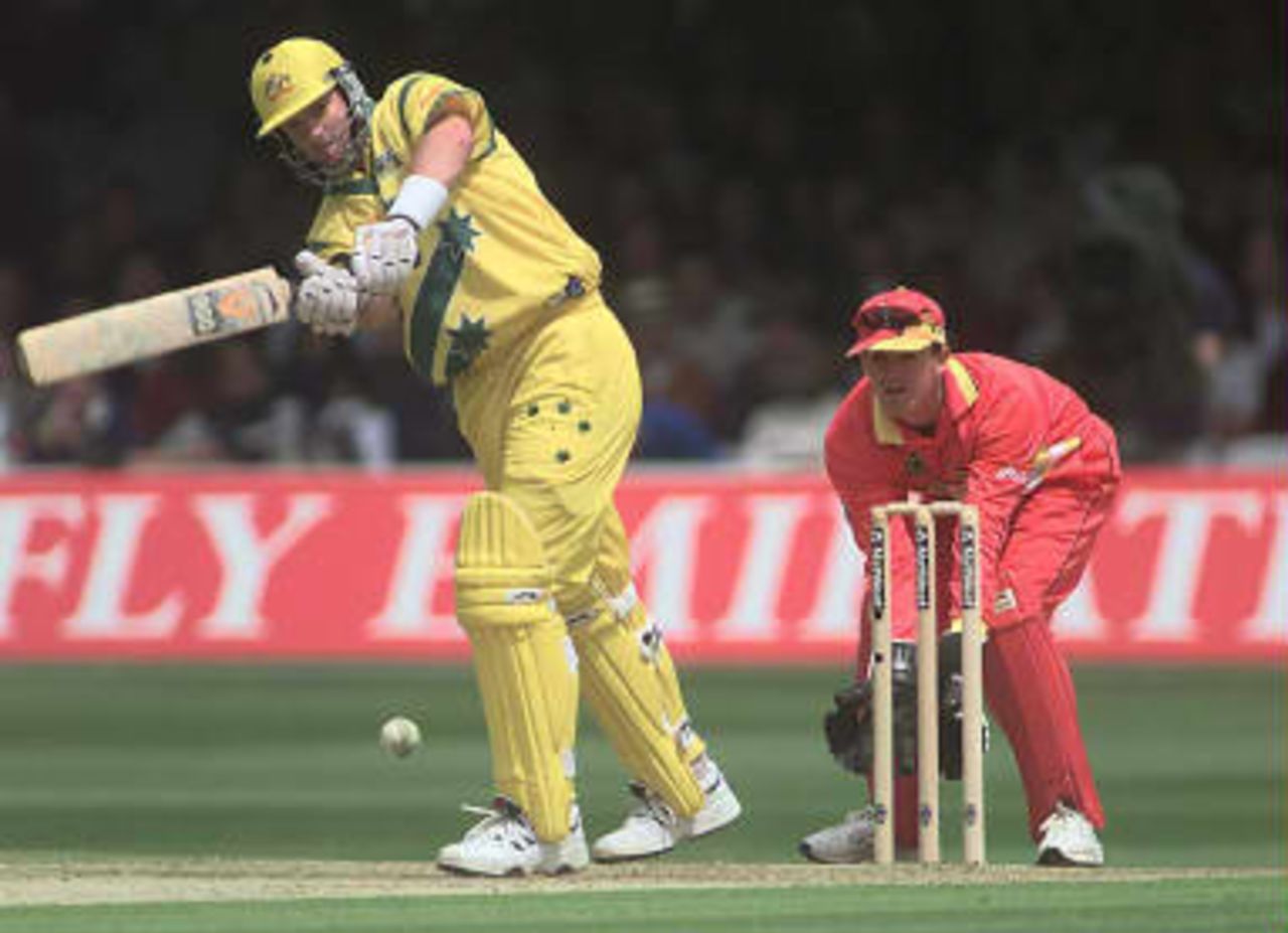 Australian batsman Mark Waugh (L) hits out on his way to 104, as Andy Flower looks on during their Cricket World Cup cricket match at Lords in London 09 June 1999