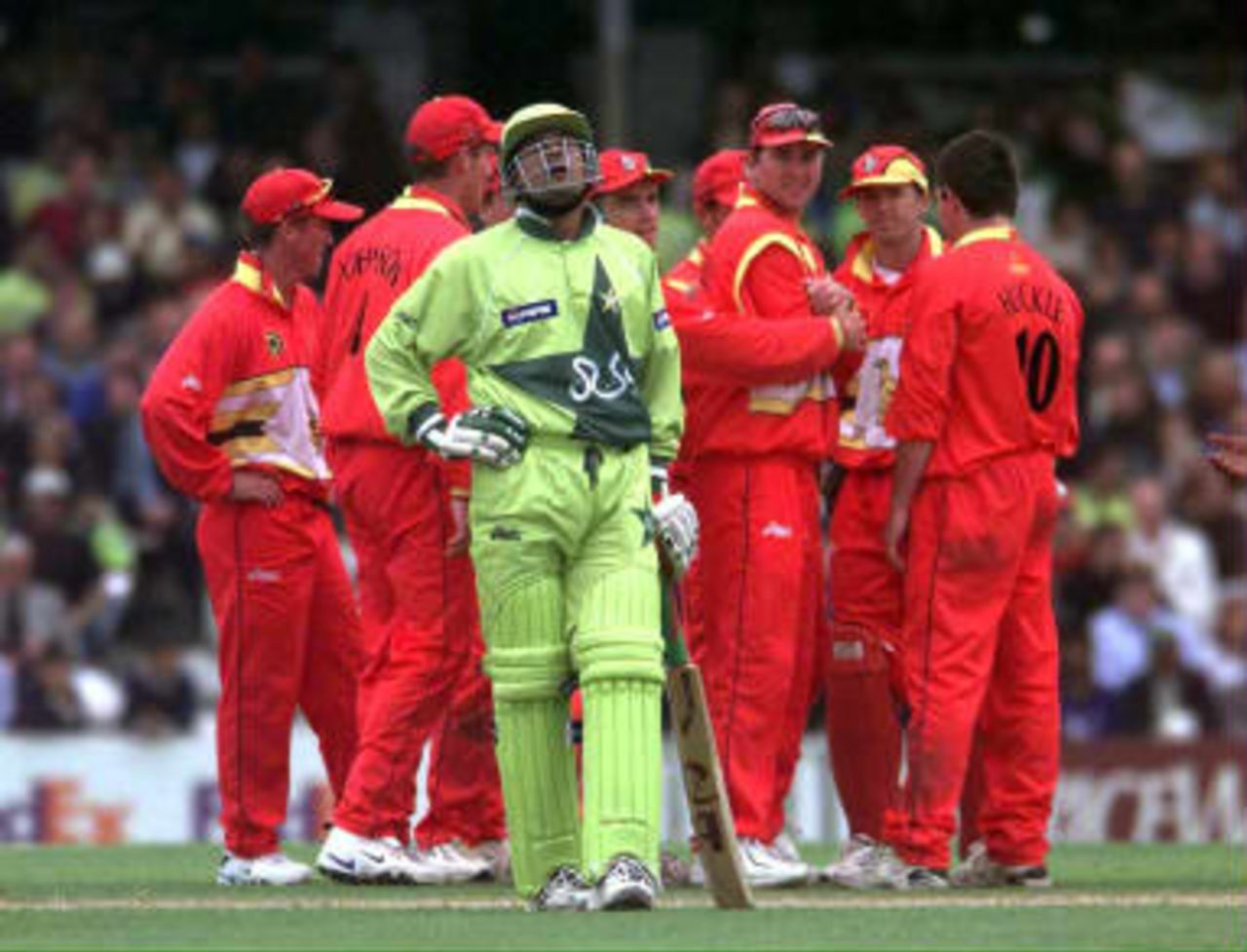 Pakistan batsman Moin Khan walks off as the Zimbabwe team celebrate his runout following the third umpire's decision during their Cricket World Cup Super Six match at The Oval in London 11 June 1999