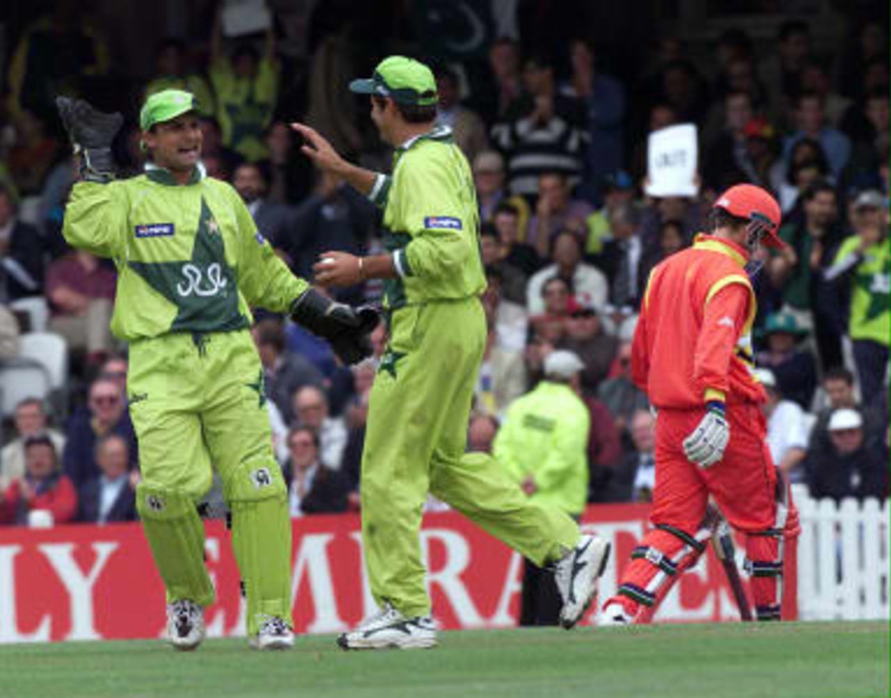 Zimbabwe`s Murray Goodwin (R) walks back to the Pavilion after being caught out by Pakistan`s Shahid Afridi (R), congratulated by keeper Moin Khan, at the Cricket World Cup match at the Oval in London 11 June 1999