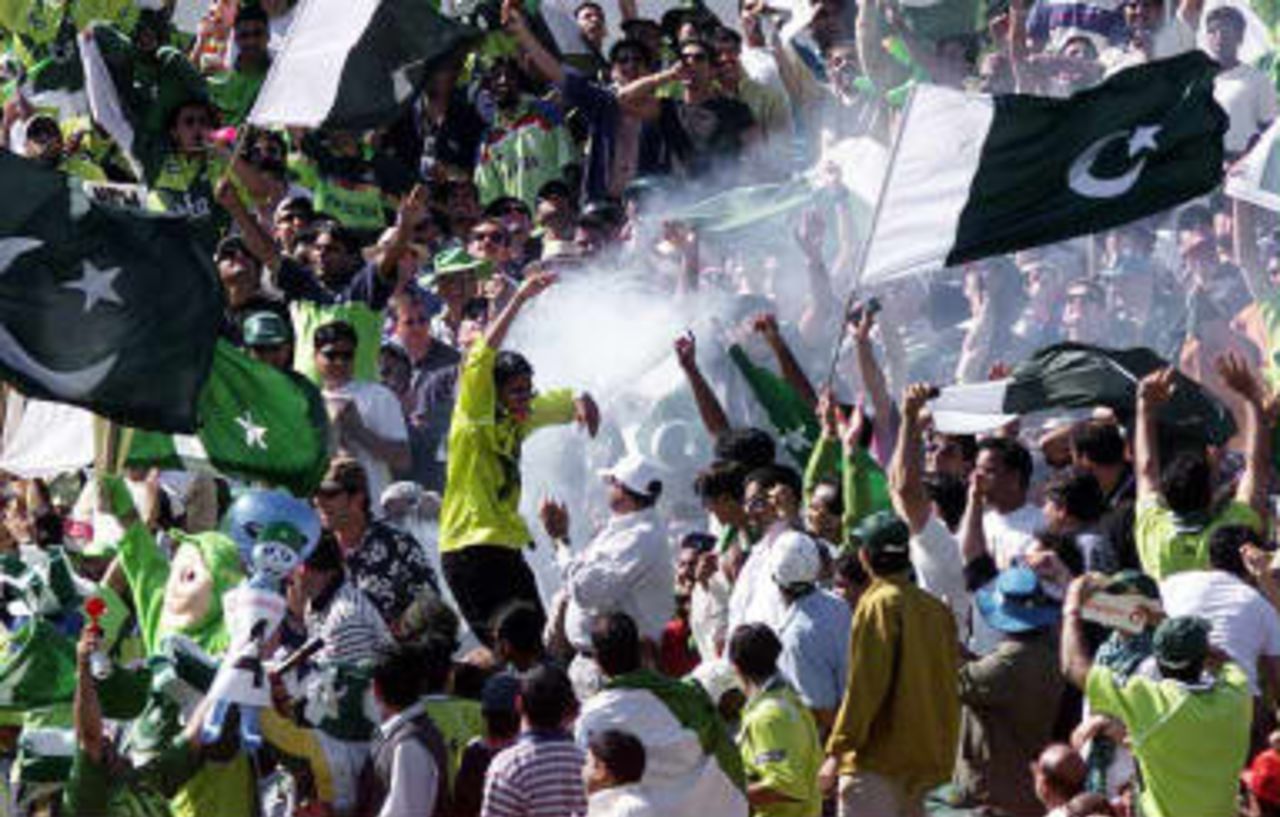 Pakistani fans dance as firecrackers and smoke bombs explode during their semi-final match against New Zealand in the Cricket World Cup at Old Trafford, Manchester, 16 June 1999.