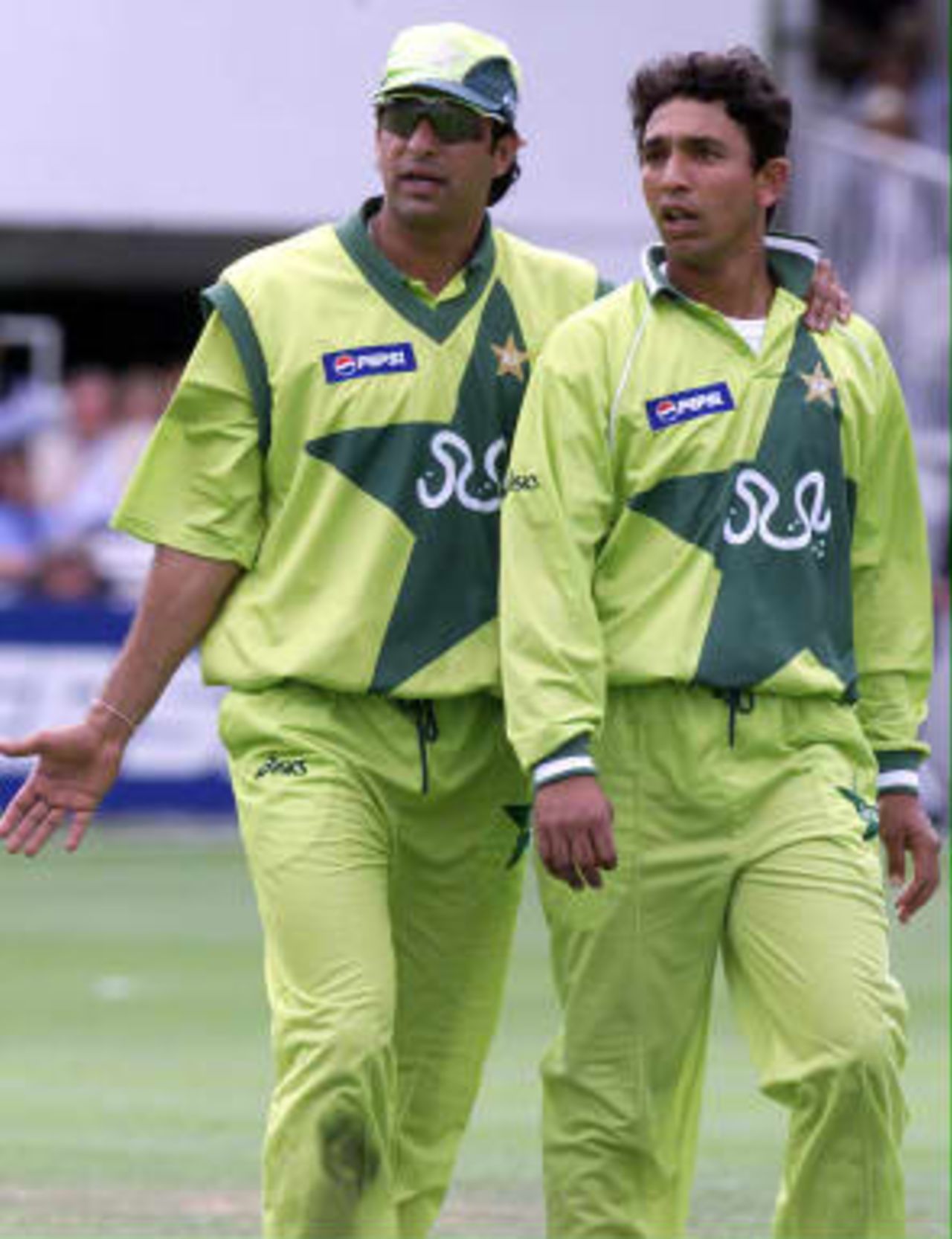 Pakistan`s captain Wasim Akram (Left) looks towards the giant TV screen with his bowler Azhar Mahmood during the World Cup cricket final at Lords in London as Australia head towards victory by eight wickets, 20 June 1999 .