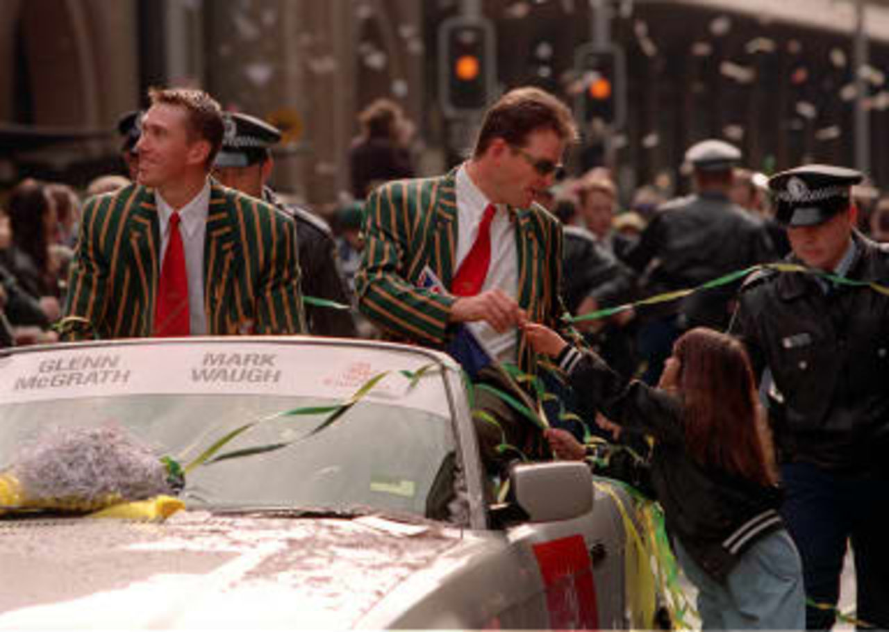 Australian batsman Mark Waugh (3rd R) signs an autograph for a young fan while fast bowler Glen McGrath (L) watches the crowd during a parade through the streets of Sydney 28 June 1999. The team was feted by some 100,000 people to mark their Wor