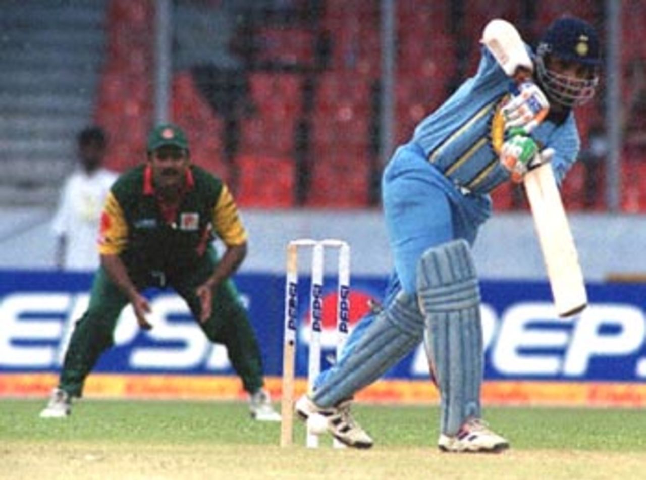 Indian captain Sourav Ganguly (R) drives during his unbeaten century against Bangladesh in the four-nation Asia Cup limited-overs tournament at the Bangabandhu national stadium in Dhaka as Bangladesh's Akram Khan watches the result. India won by eight wickets. Asia Cup 1999/00, 2nd Match, Bangladesh v India, Bangabandhu National Stadium, Dhaka. 30-31 May 2000.