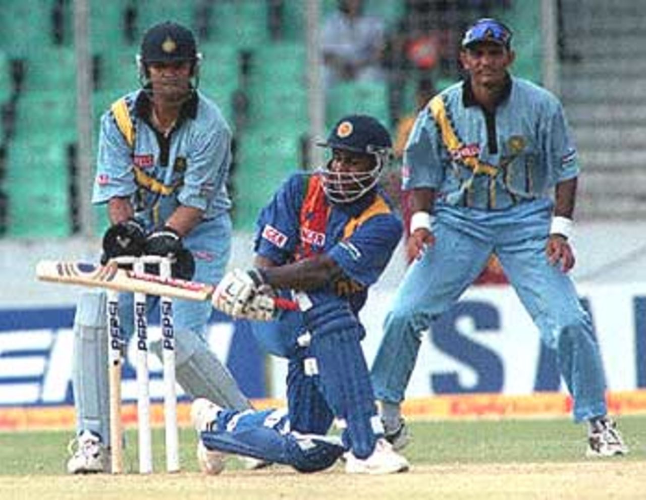Indian wicketkeeper Rahul Dravid (L) and former captain Mohammad Azharuddin (R) watch Sri Lankan skipper Sanath Jayasuriya (C) batting during his knock of 105 of 116 balls against India in the four-nation Asia Cup limited-overs tournament at the Bangabandhu national stadium in Dhaka. India restricted Sri Lanka 276-8. Asia Cup, 1999/00, 3rd Match, India v Sri Lanka, Bangabandhu National Stadium, Dhaka. 1 June 2000.