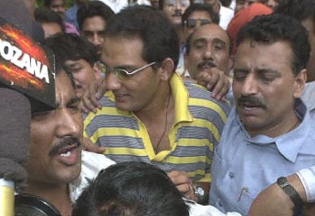Former India cricket captain Mohammad Azharuddin (C) is mobbed by reporters as he leaves the Central Bureau of Investigation (CBI) accompanied by CBI agents 22 June 2000. Azharuddin was brought in for questioning after disgraced South African captain Hansie Cronje named him in a case of match fixing.